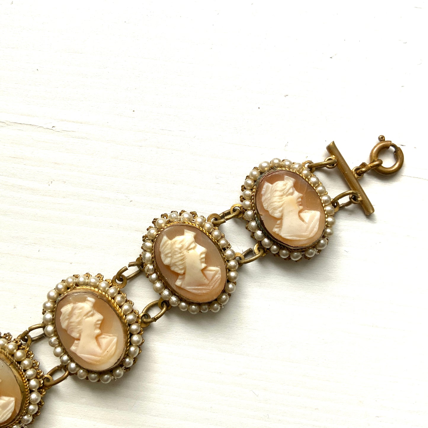 A bracelet lavishly set with seven shell cameos, each delicately framed with tiny glass pearls. 七つのシェルカメオを贅沢に連ねたブレスレット。