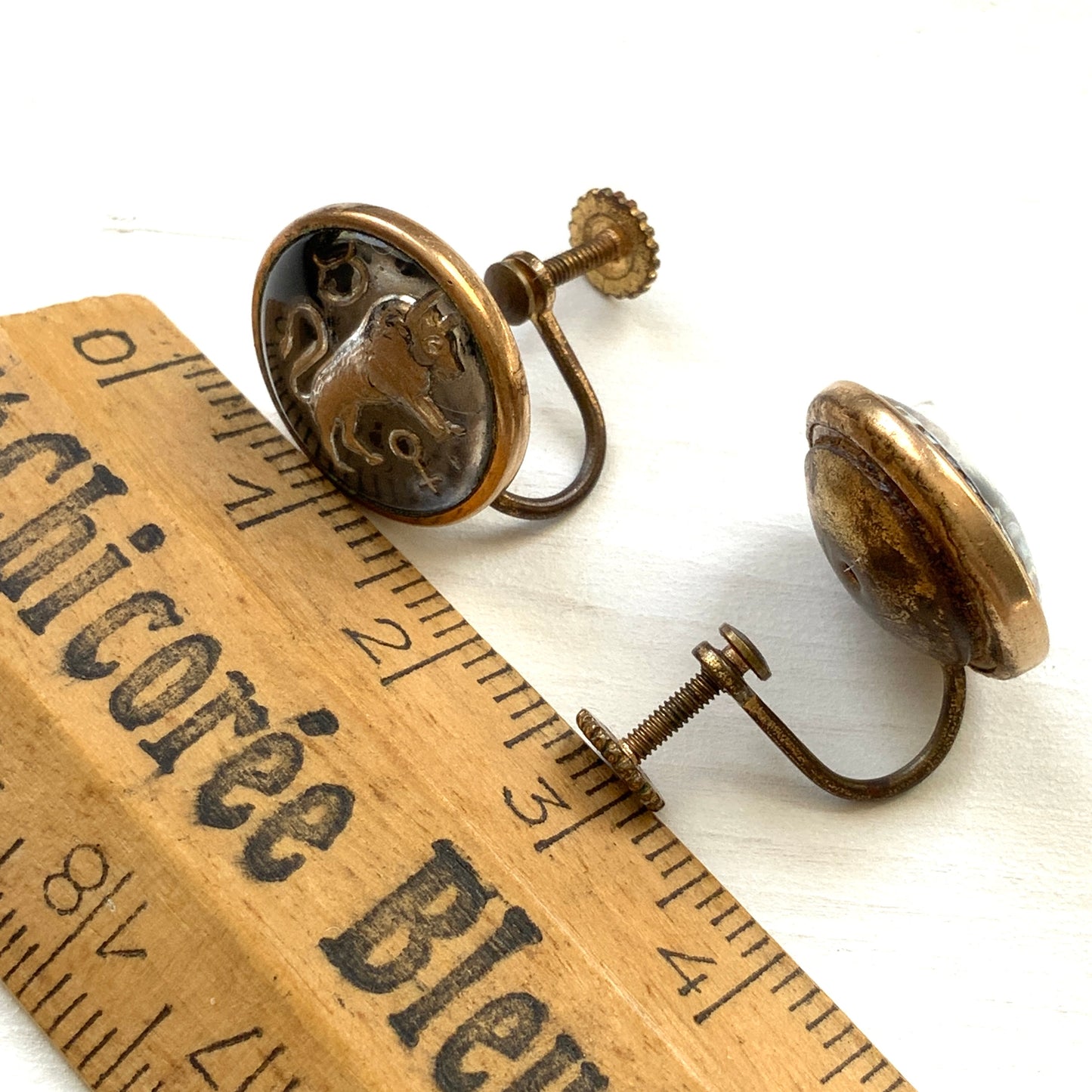 Screw-back earrings featuring an reverse carved design of a Taurus bull . 黒地にゴールドトーンで牡牛とそのシンボルが裏彫りされた、ヴィンテージのスクリューイヤリング。