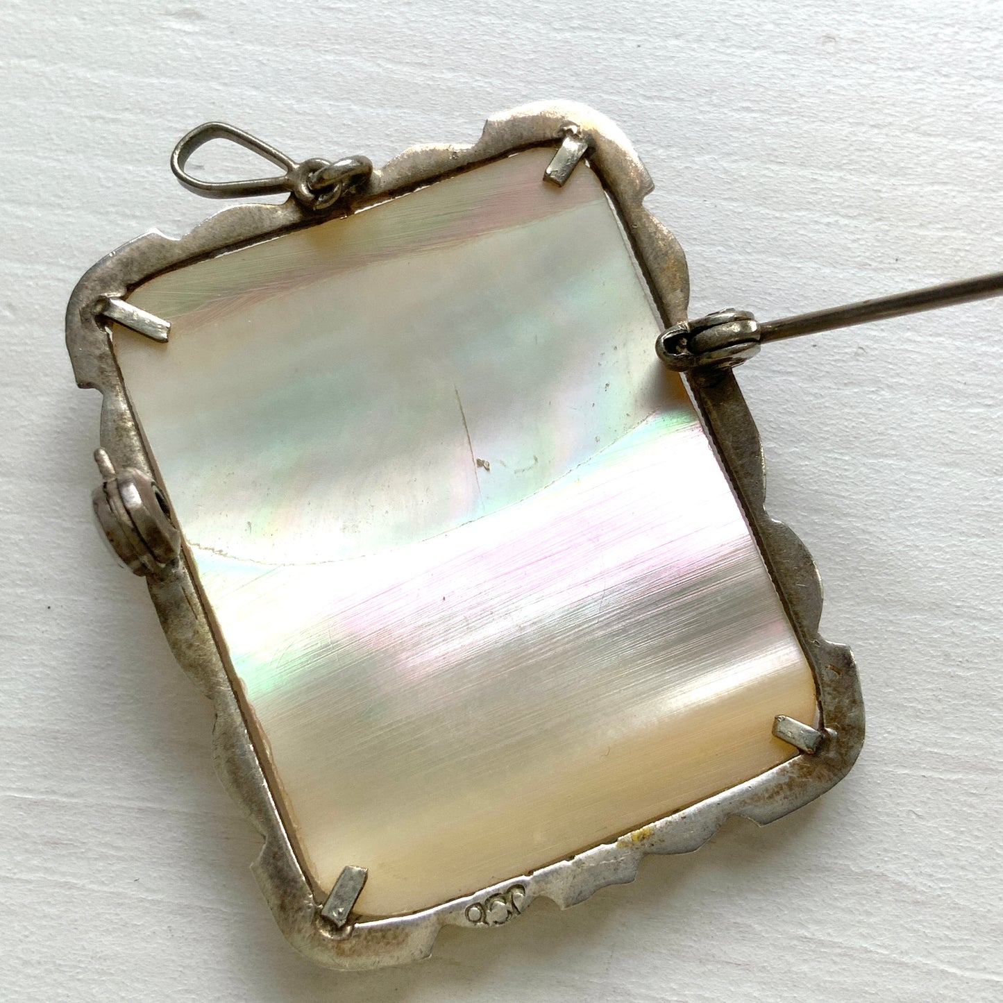 A brooch featuring a cameo of a lady’s profile carved in black mother of pearl, set against a white mother of pearl base. 白蝶貝をベースに、黒蝶貝で女性の横顔カメオをあしらったブローチ。