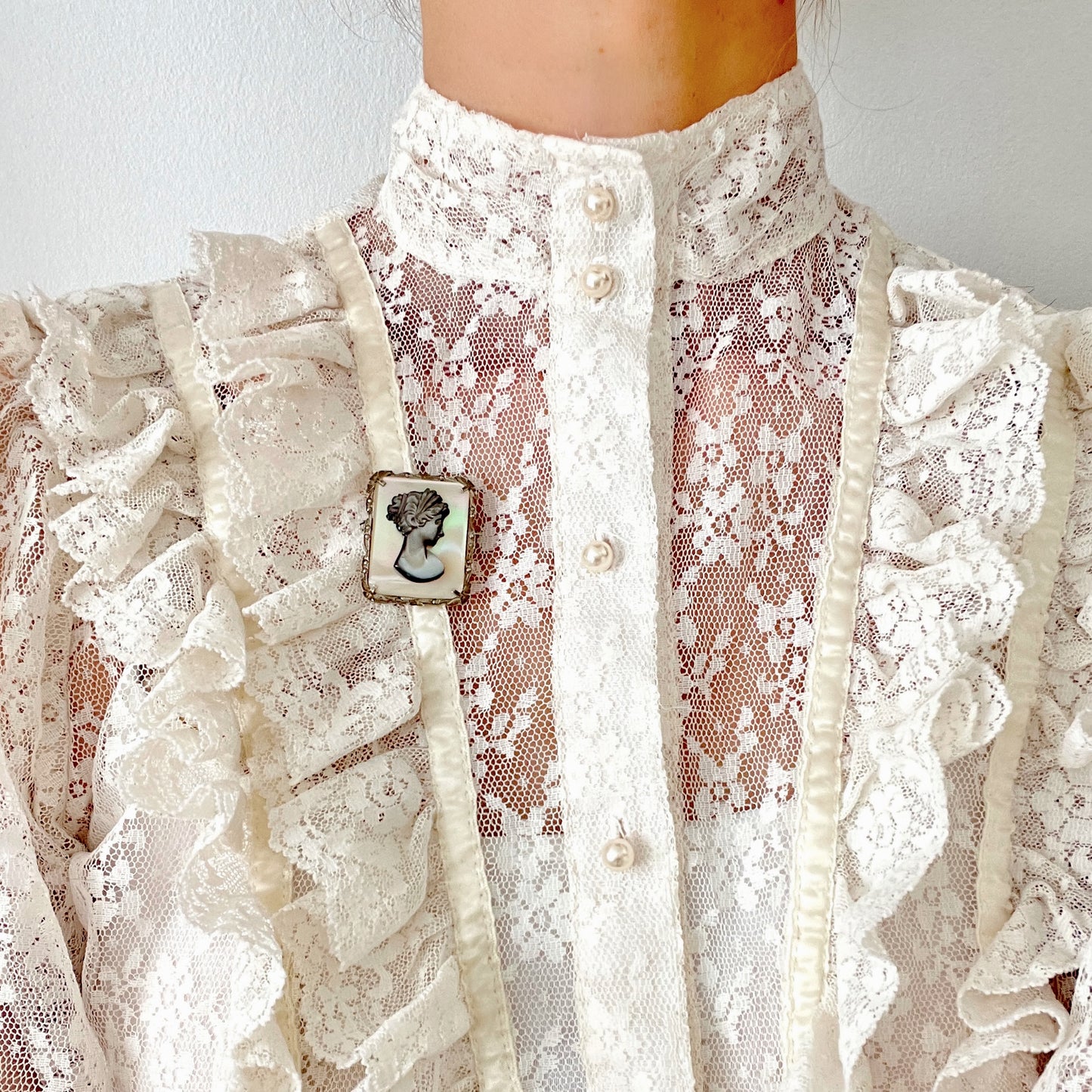 A brooch featuring a cameo of a lady’s profile carved in black mother of pearl, set against a white mother of pearl base. 白蝶貝をベースに、黒蝶貝で女性の横顔カメオをあしらったブローチ。