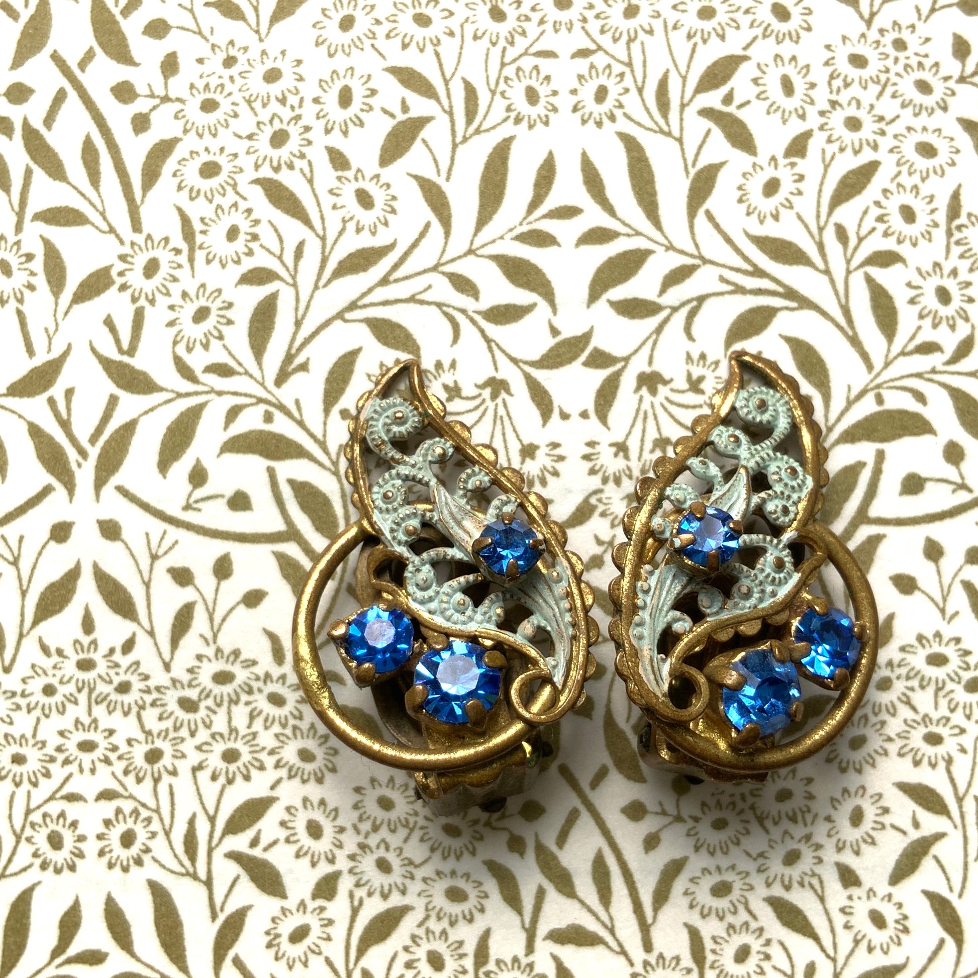 Clip-on earrings in the shape of filigree feathers, delicately painted in light blue. 水色にペイントされたフィリグリーの羽の形のクリップイヤリング。