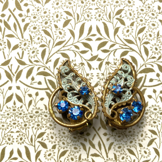 Clip-on earrings in the shape of filigree feathers, delicately painted in light blue. 水色にペイントされたフィリグリーの羽の形のクリップイヤリング。