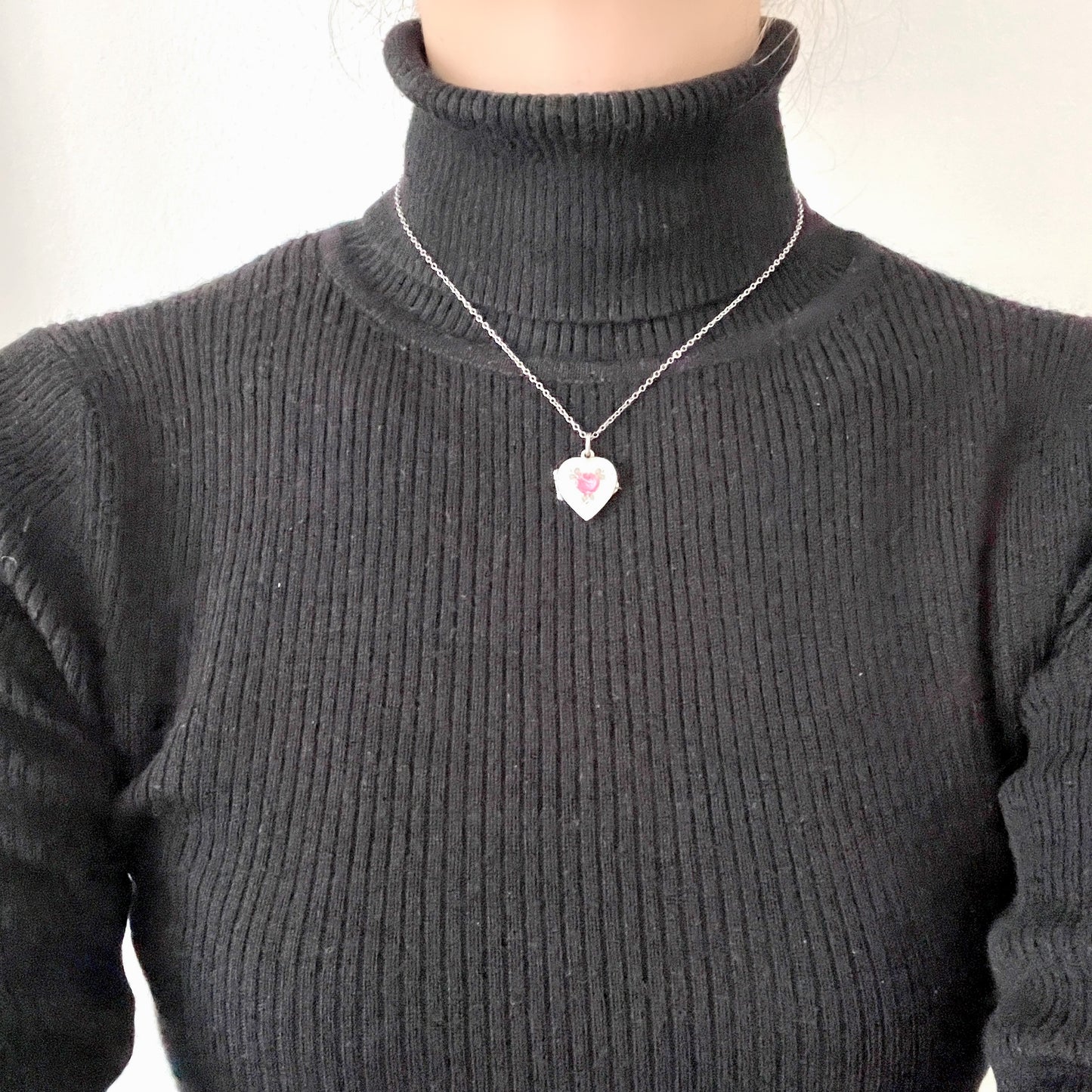 A silver heart locket featuring white guilloché enamel with a very subtle pale mint-green undertone, decorated with a rose motif. ごく淡いミントグリーンのシェードを含んだホワイトギヨシェエナメルに、薔薇のモチーフが描かれたシルバーのハートロケット。