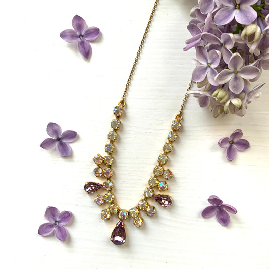 A necklace featuring white aurora borealis, accented with lilac-coloured teardrop rhinestones. ホワイトのオーロラストーンに、ライラックカラーのティアドロップラインストーン がアクセントになったネックレス。