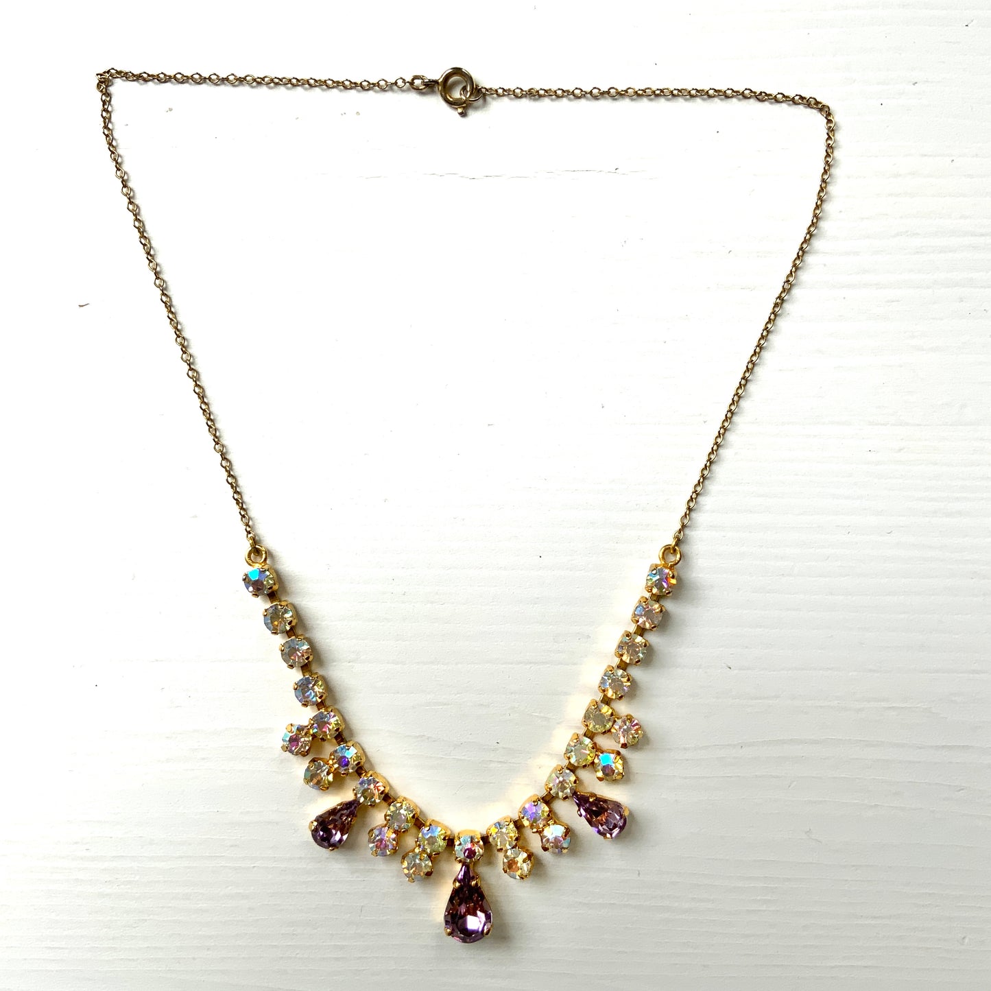 A necklace featuring white aurora borealis, accented with lilac-coloured teardrop rhinestones. ホワイトのオーロラストーンに、ライラックカラーのティアドロップラインストーン がアクセントになったネックレス。