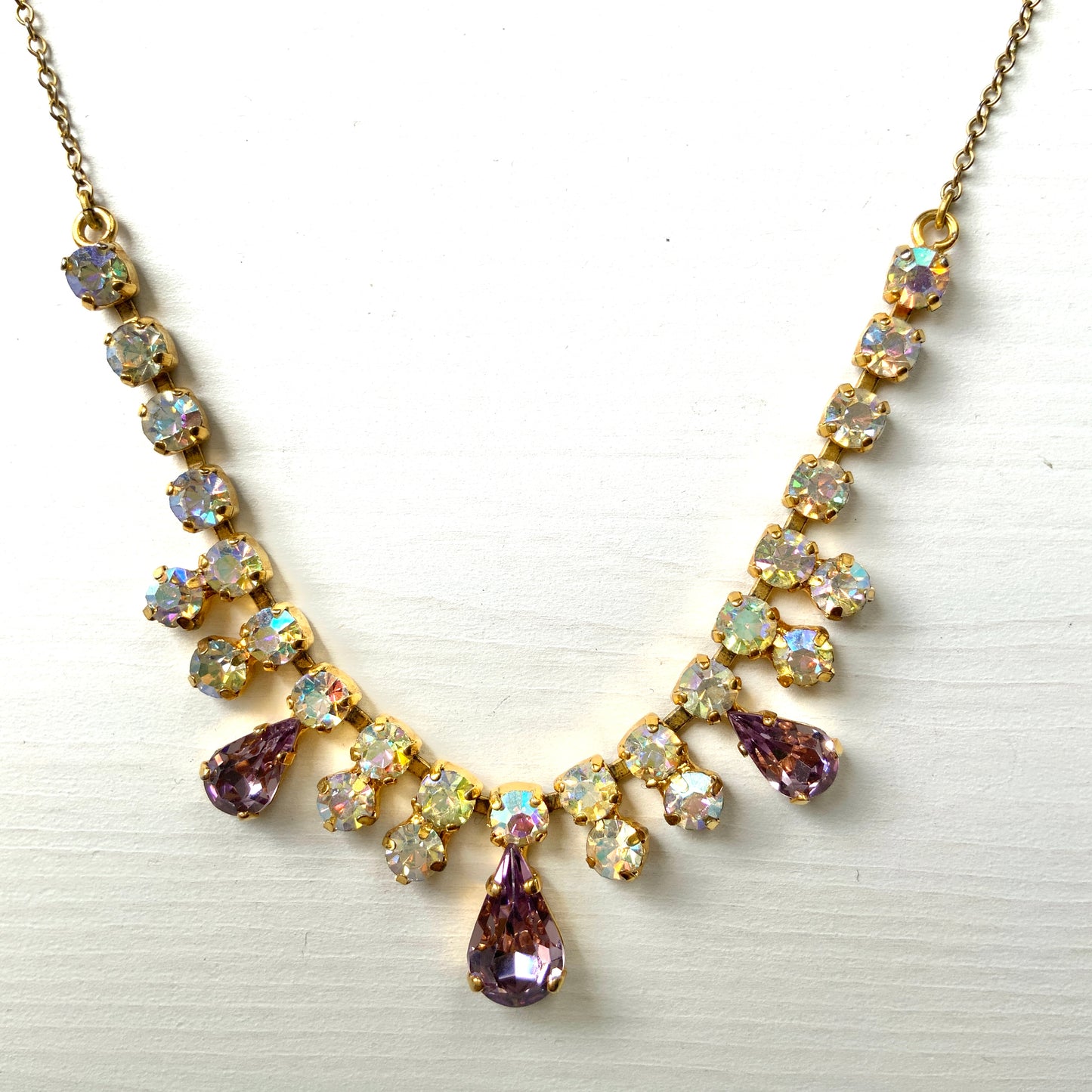 A necklace featuring white aurora borealis, accented with lilac-coloured teardrop rhinestones. ホワイトのオーロラストーンに、ライラックカラーのティアドロップラインストーン がアクセントになったネックレス。