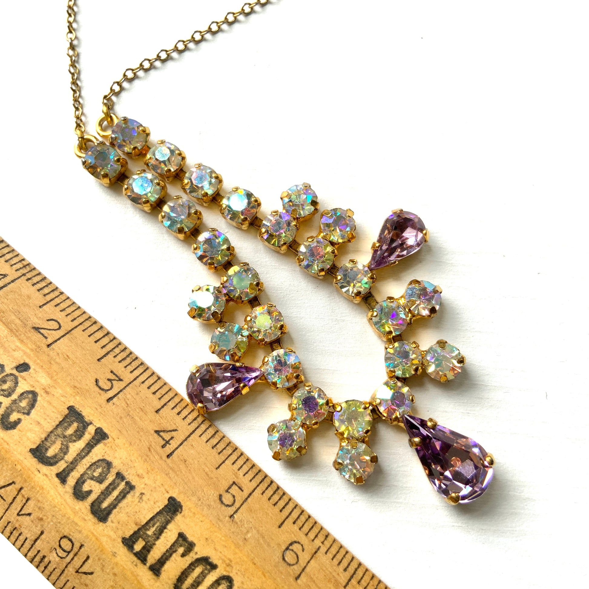 A necklace featuring white aurora borealis, accented with lilac-coloured teardrop rhinestones. ホワイトのオーロラストーンに、ライラックカラーのティアドロップラインストーン がアクセントになったネックレス。