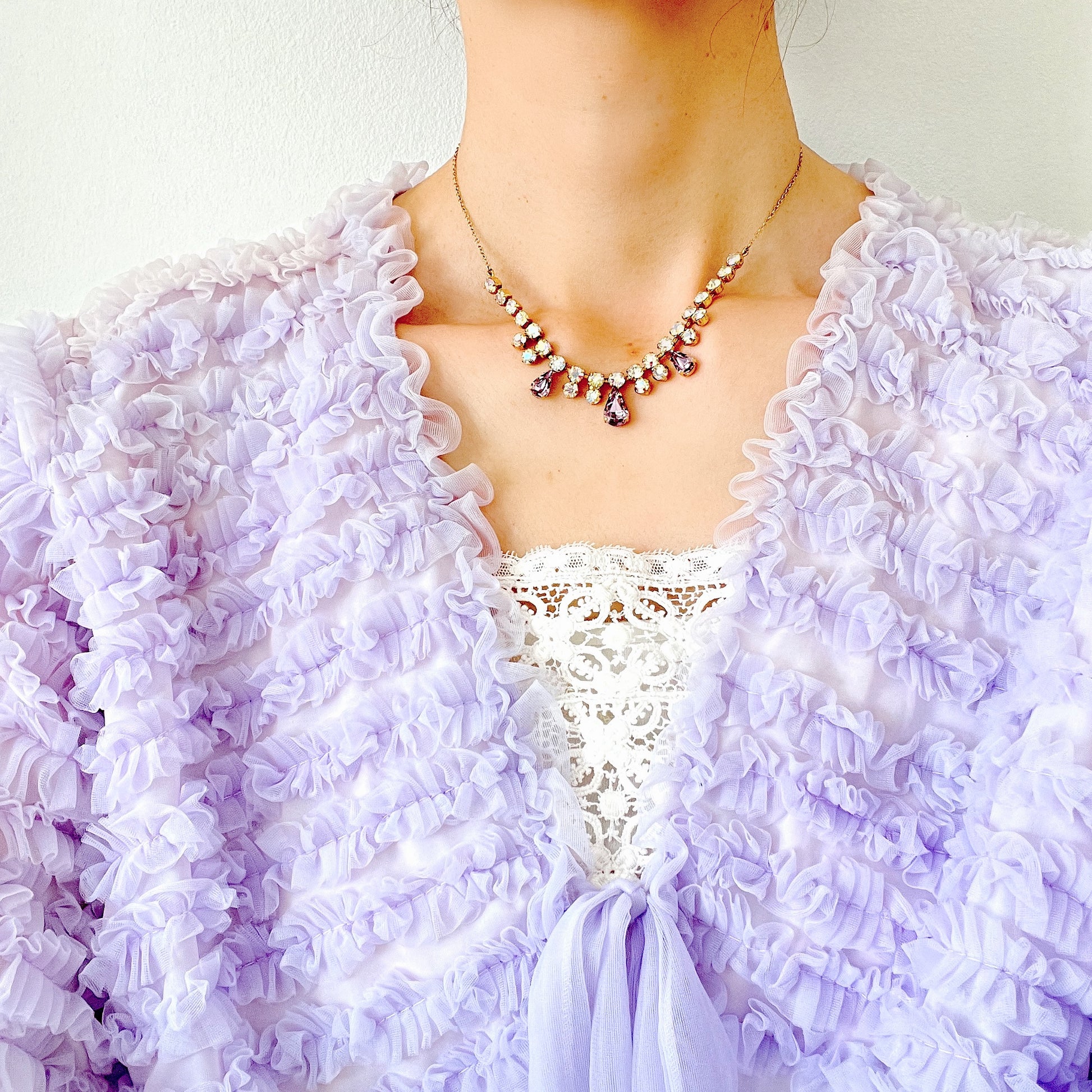 A necklace featuring white aurora borealis, accented with lilac-coloured teardrop rhinestones. ホワイトのオーロラストーンに、ライラックカラーのティアドロップラインストーン がアクセントになったネックレス。