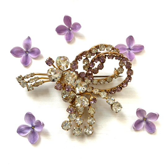 A gorgeous brooch featuring clear and lilac-colored rhinestones.  クリアカラーとライラックカラーのラインストーンのゴージャスなブローチ。