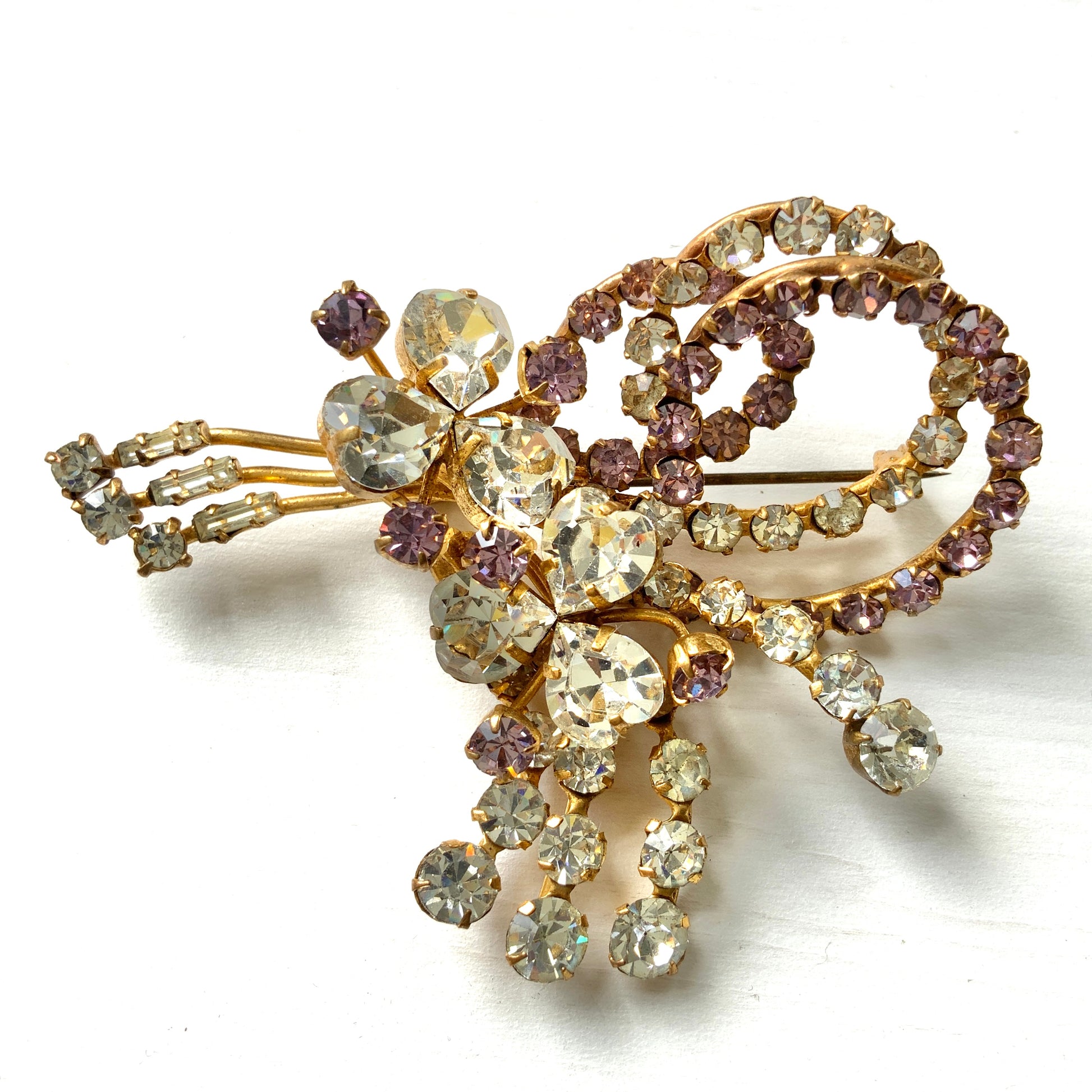 A gorgeous brooch featuring clear and lilac-colored rhinestones.  クリアカラーとライラックカラーのラインストーンのゴージャスなブローチ。