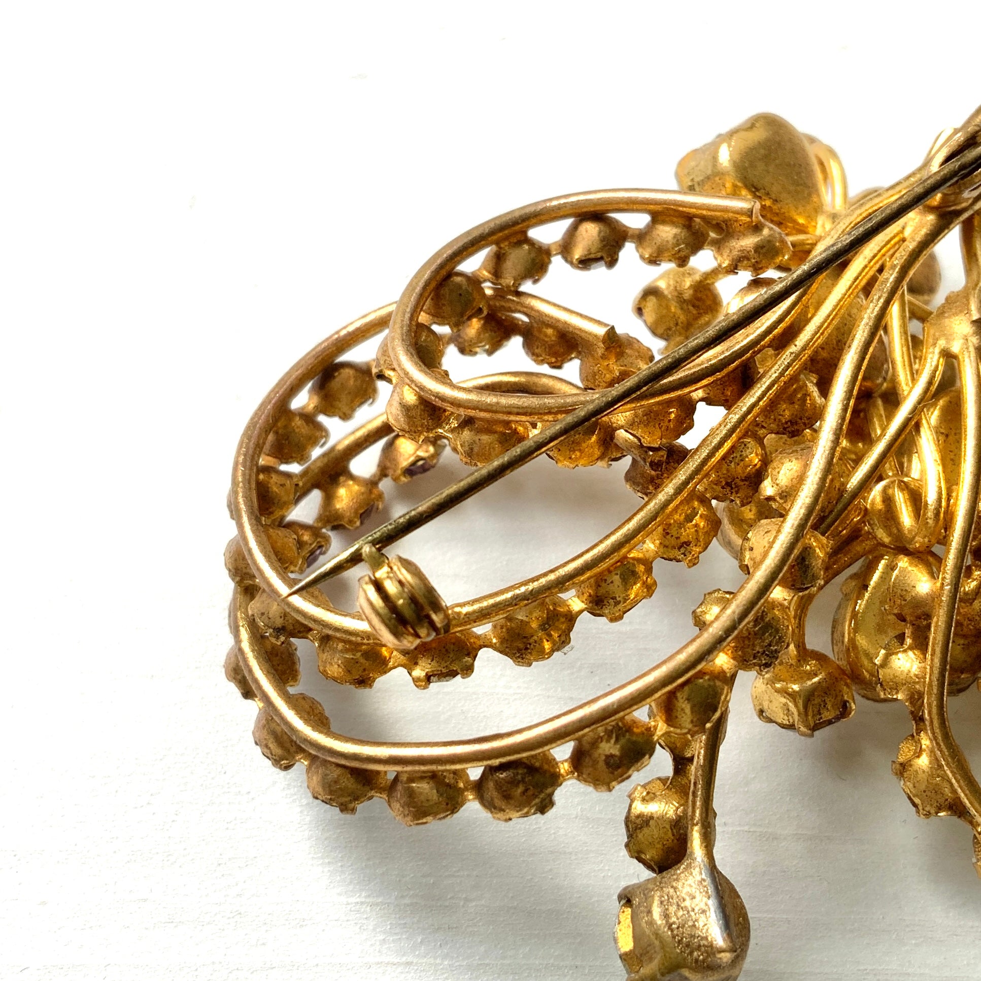 A gorgeous brooch featuring clear and lilac-colored rhinestones.  クリアカラーとライラックカラーのラインストーンのゴージャスなブローチ。