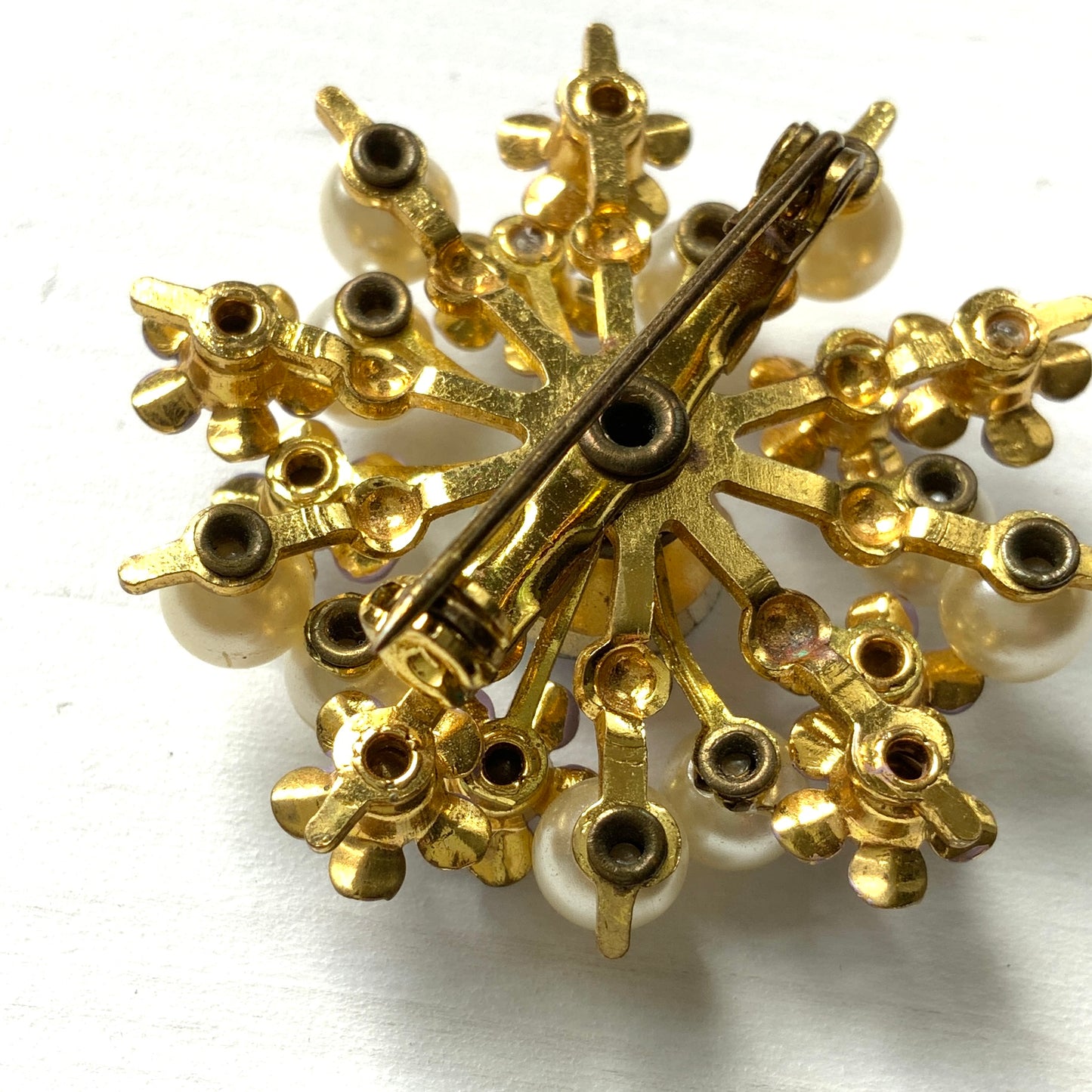 A brooch centered around large lilac-colored aurora borealis, adorned with small lilac enamel flowers and glass pearls. 大粒のライラックカラーのオーロラストーンを中心に、ライラックカラーのエナメルの小花とグラスパールがあしらわれたブローチ。