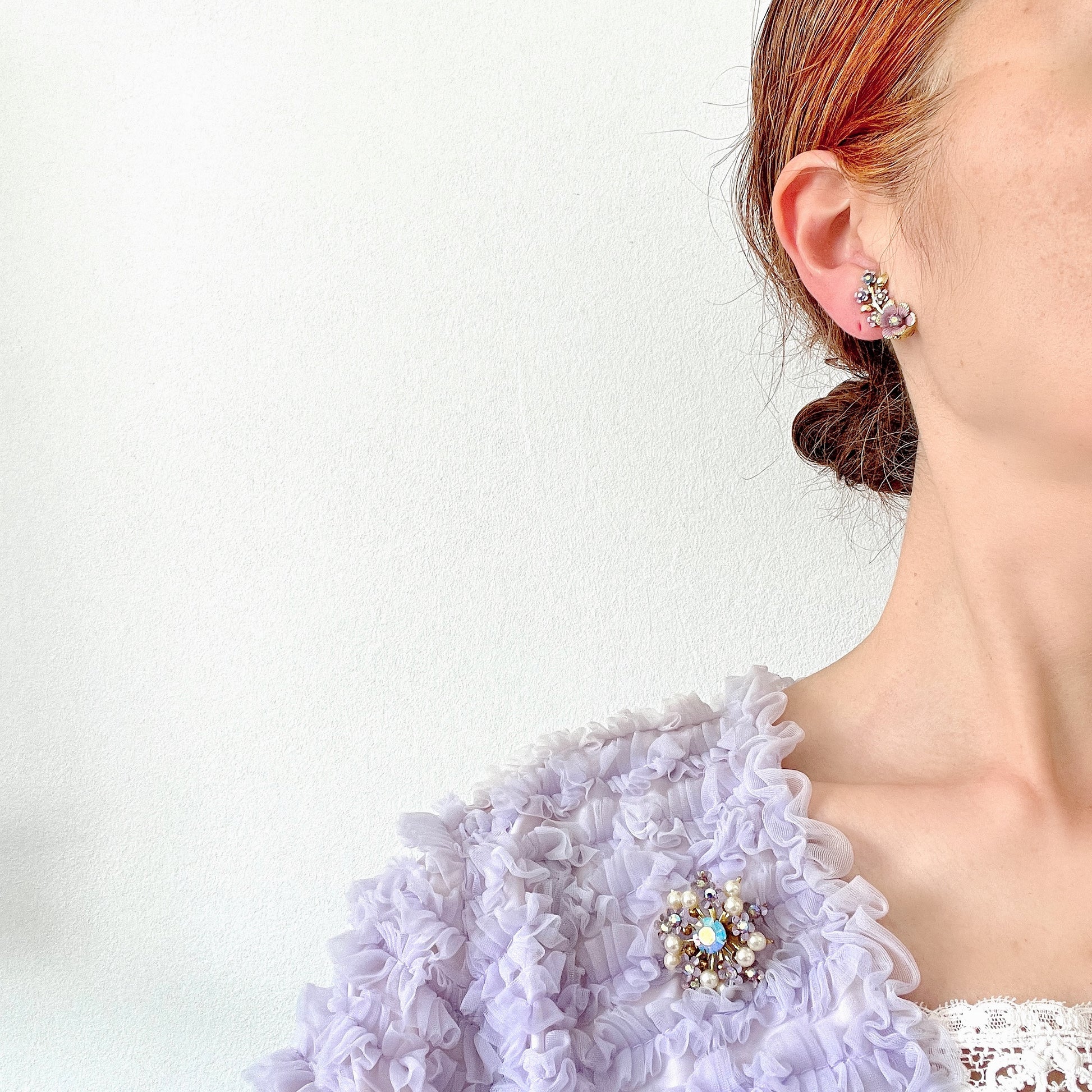 A brooch centered around large lilac-colored aurora borealis, adorned with small lilac enamel flowers and glass pearls. 大粒のライラックカラーのオーロラストーンを中心に、ライラックカラーのエナメルの小花とグラスパールがあしらわれたブローチ。