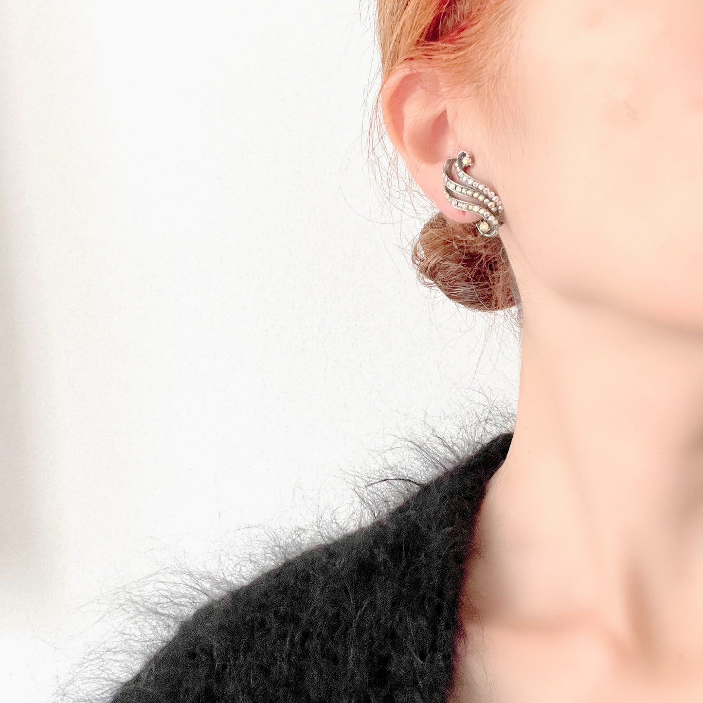 Clip-on earrings featuring aurora borealis rhinestones that trace a graceful curved line. 虹色に輝くオーロラストーンが緩やかなラインを描くクリップイヤリング。