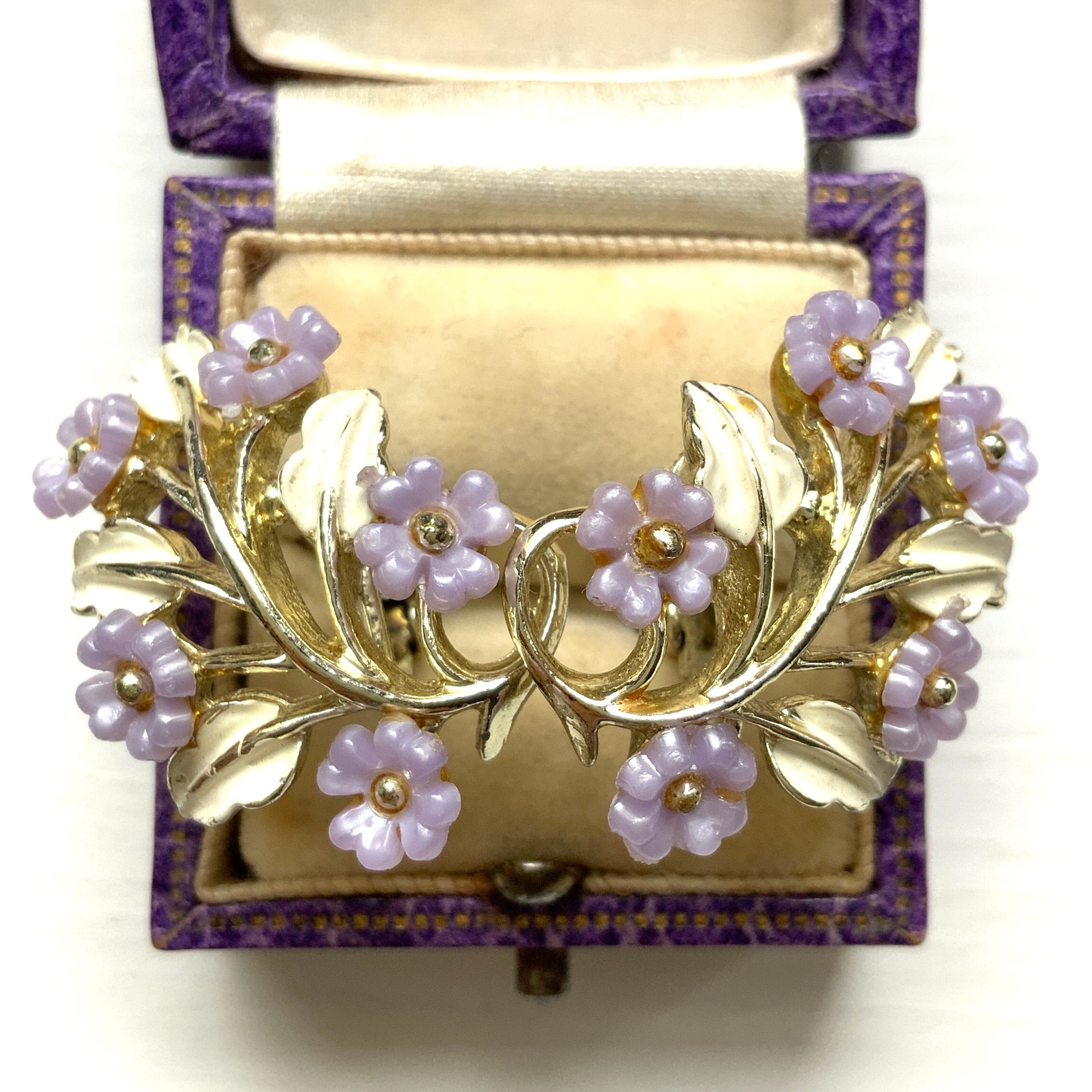 Charming clip-on earrings with pale purple blossoms adorning white enameled leaves. 白いエナメルの葉っぱに、かわいらしい薄紫のお花が咲いたクリップイヤリング。