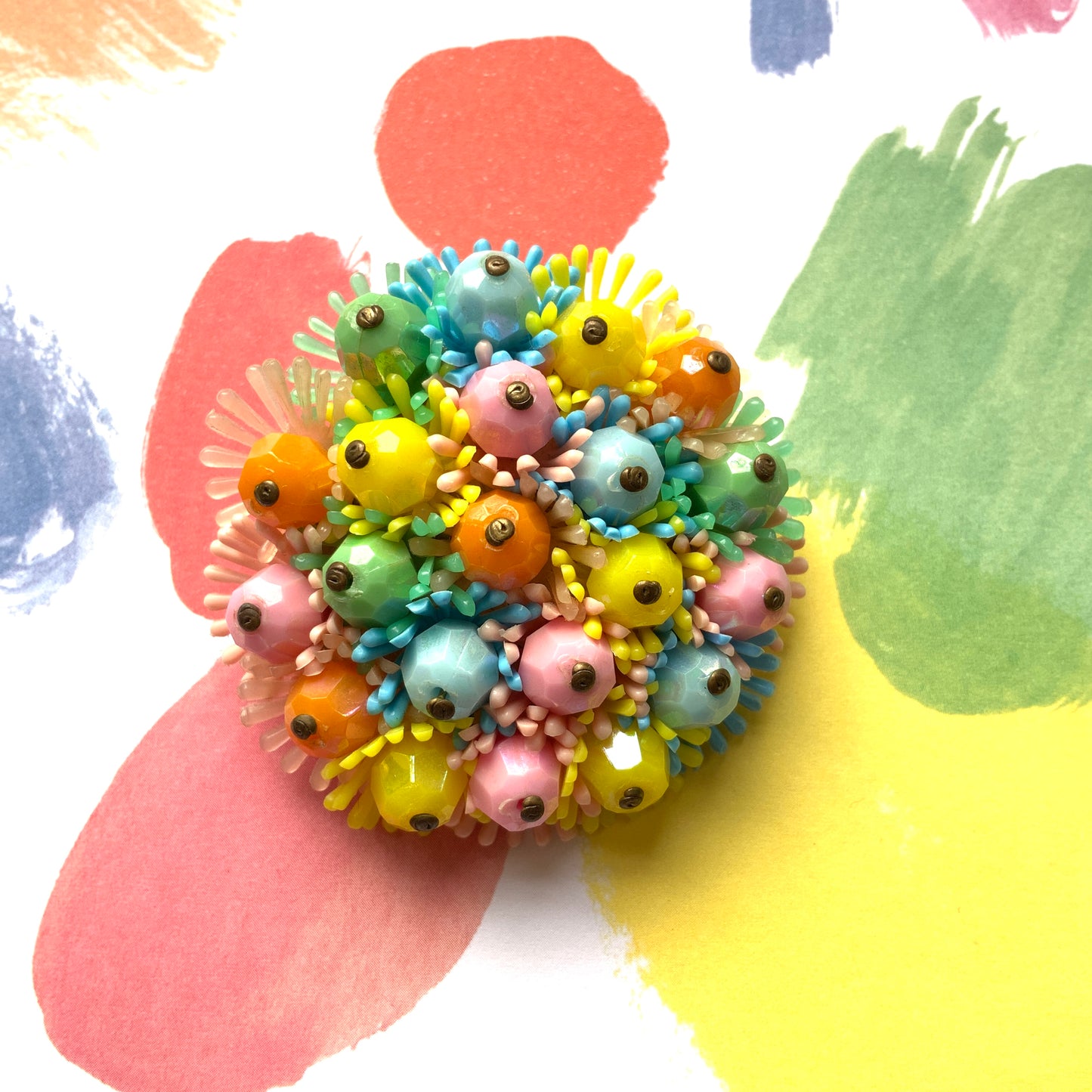 A round brooch featuring colourful candy-coloured soft plastic flowers. カラフルなキャンディーカラーのソフトプラスチックのお花が集まったラウンドブローチ。