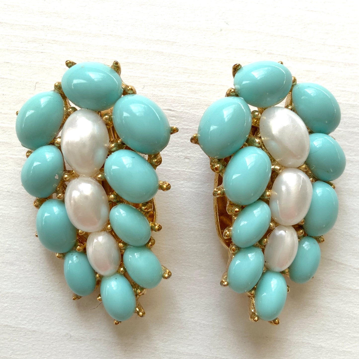 A Trifari dress clip featuring a pure white faux baroque pearl, beautifully framed by pastel turquoise plastic cabochons. ピュアホワイトカラーのフォーバロックパール を、パステルターコイズのプラスチックカボションが囲んでいる、トリファリのドレスクリップ。