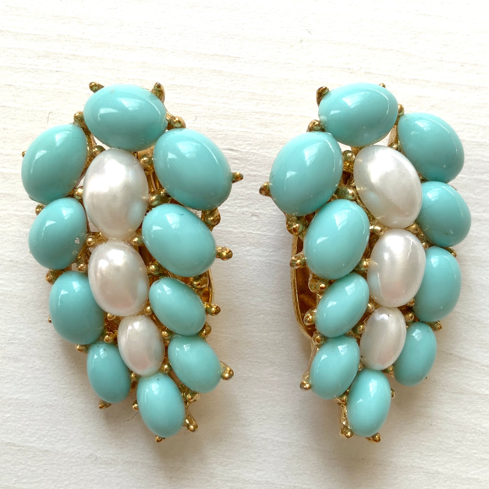 A Trifari dress clip featuring a pure white faux baroque pearl, beautifully framed by pastel turquoise plastic cabochons. ピュアホワイトカラーのフォーバロックパール を、パステルターコイズのプラスチックカボションが囲んでいる、トリファリのドレスクリップ。