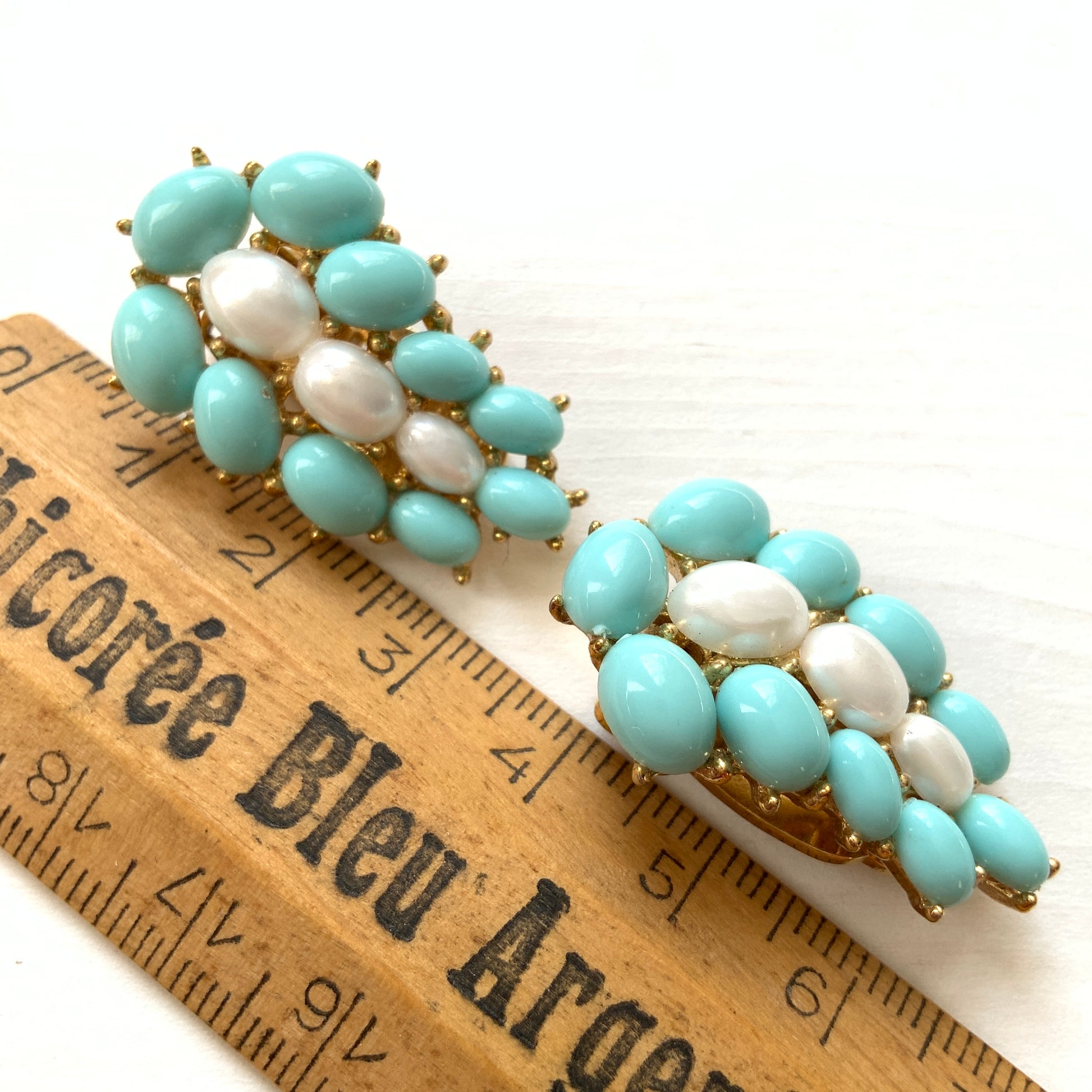 A Trifari dress clip featuring a pure white faux baroque pearl, beautifully framed by pastel turquoise plastic cabochons. ピュアホワイトカラーのフォーバロックパール を、パステルターコイズのプラスチックカボションが囲んでいる、トリファリのドレスクリップ。