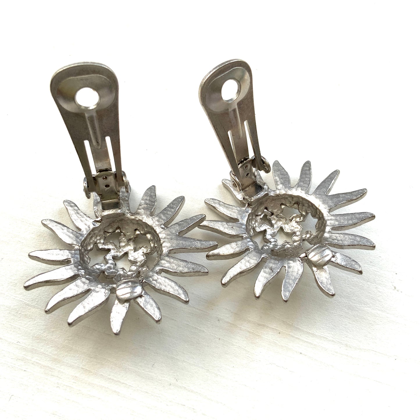 Clip-on earrings featuring a silver-tone sun motif with star-shaped cut-outs. シルバートーンの太陽モチーフに、星型のカットアウトが施されたクリップイヤリング。