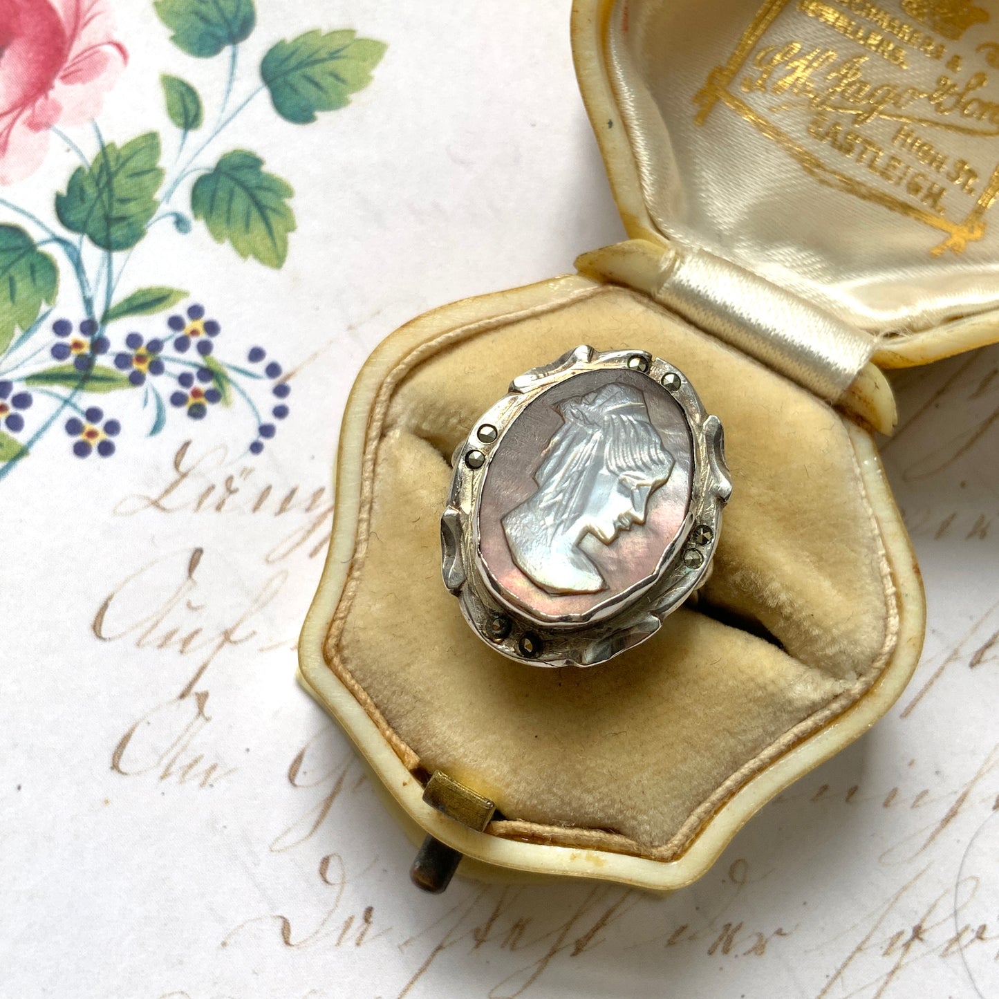 A silver ring with a cameo carved from mother of pearl, featuring the white layer carved into the profile of a lady against an iridescent grey-pink background. 白蝶貝(マザーオブパール)の白い層を彫り出し、グレー〜ピンクがかった虹色の層を背景にしたカメオのシルバーリング。