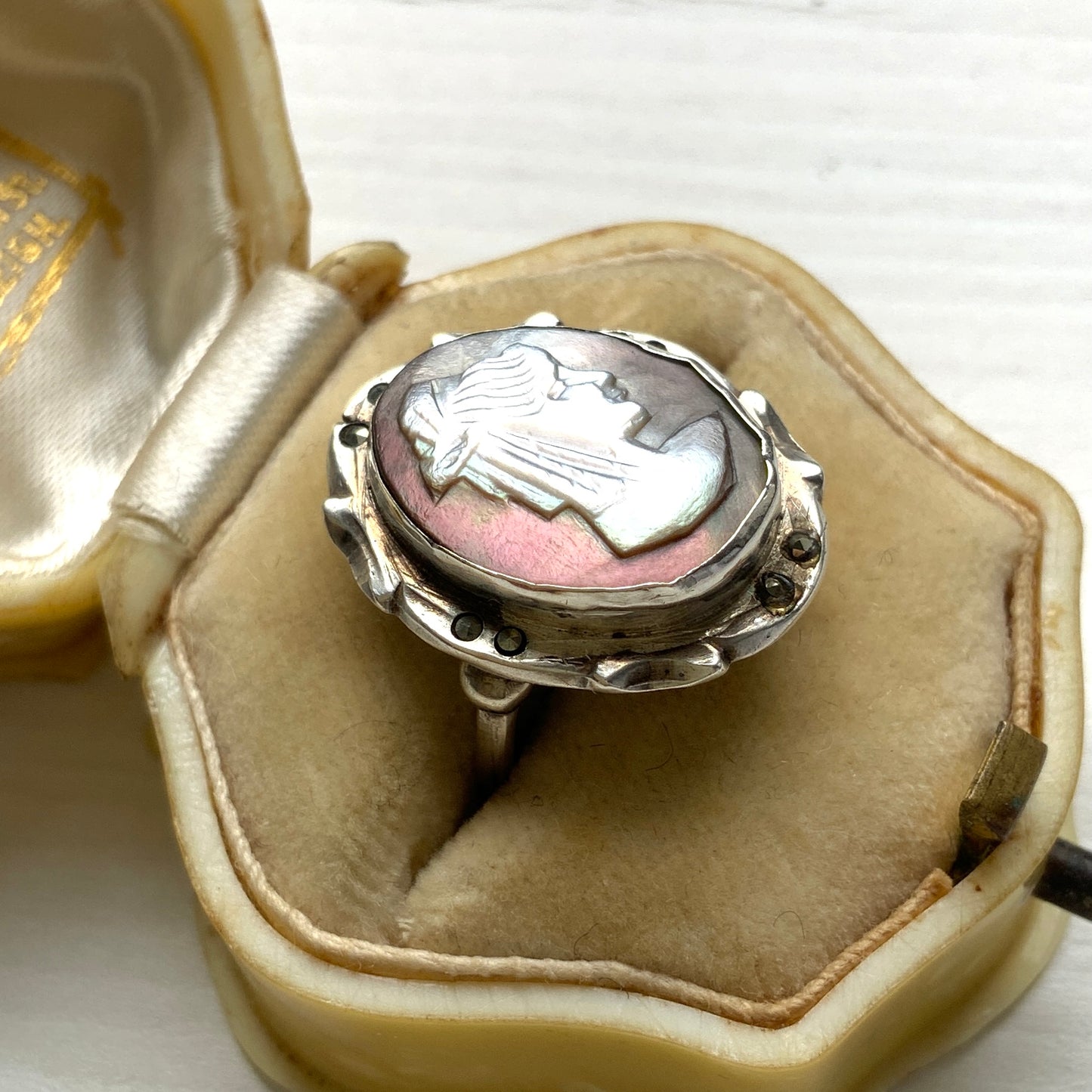 A silver ring with a cameo carved from mother of pearl, featuring the white layer carved into the profile of a lady against an iridescent grey-pink background. 白蝶貝(マザーオブパール)の白い層を彫り出し、グレー〜ピンクがかった虹色の層を背景にしたカメオのシルバーリング。