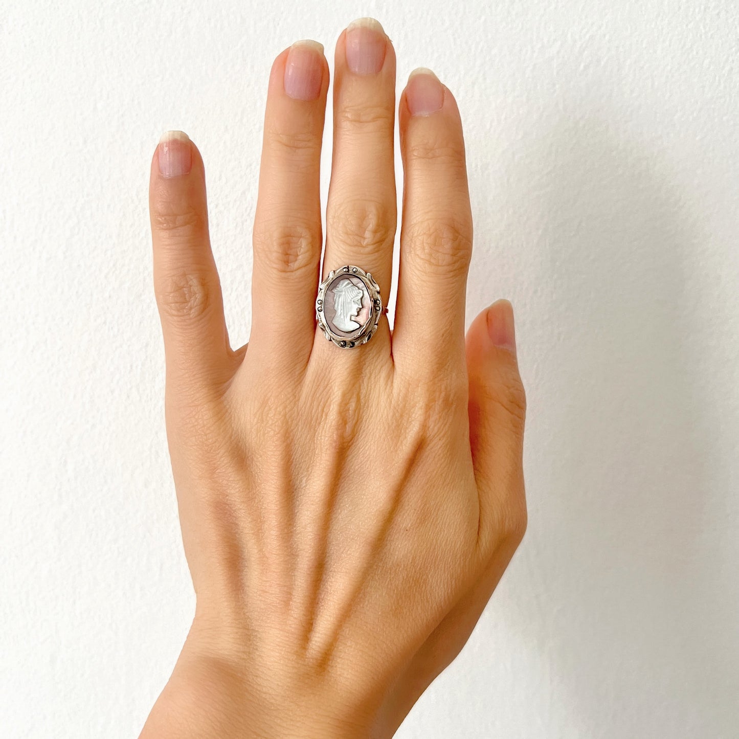 A silver ring with a cameo carved from mother of pearl, featuring the white layer carved into the profile of a lady against an iridescent grey-pink background. 白蝶貝(マザーオブパール)の白い層を彫り出し、グレー〜ピンクがかった虹色の層を背景にしたカメオのシルバーリング。