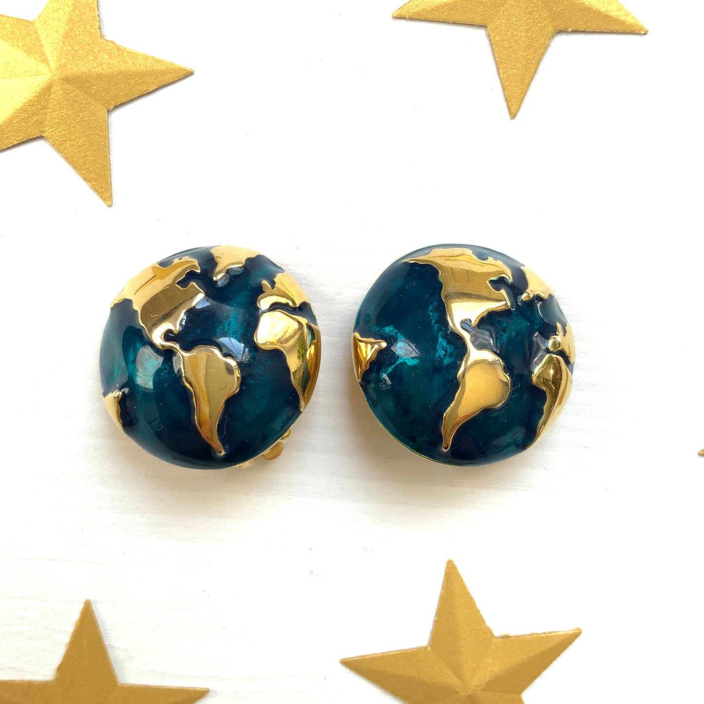 Clip-on earrings featuring a globe design with gold tone continents over a dome of deep ocean blue enamel. 深い海の色のエナメルドームにゴールドトーンで大陸をあしらった地球のクリップイヤリング。