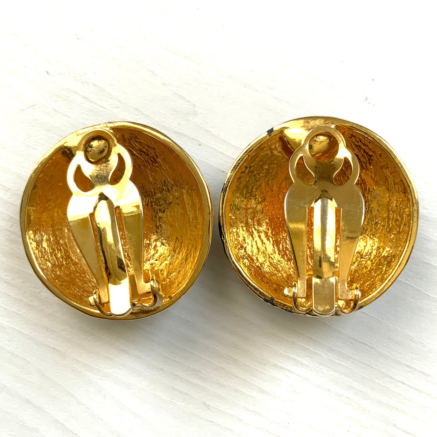 Clip-on earrings featuring a globe design with gold tone continents over a dome of deep ocean blue enamel. 深い海の色のエナメルドームにゴールドトーンで大陸をあしらった地球のクリップイヤリング。