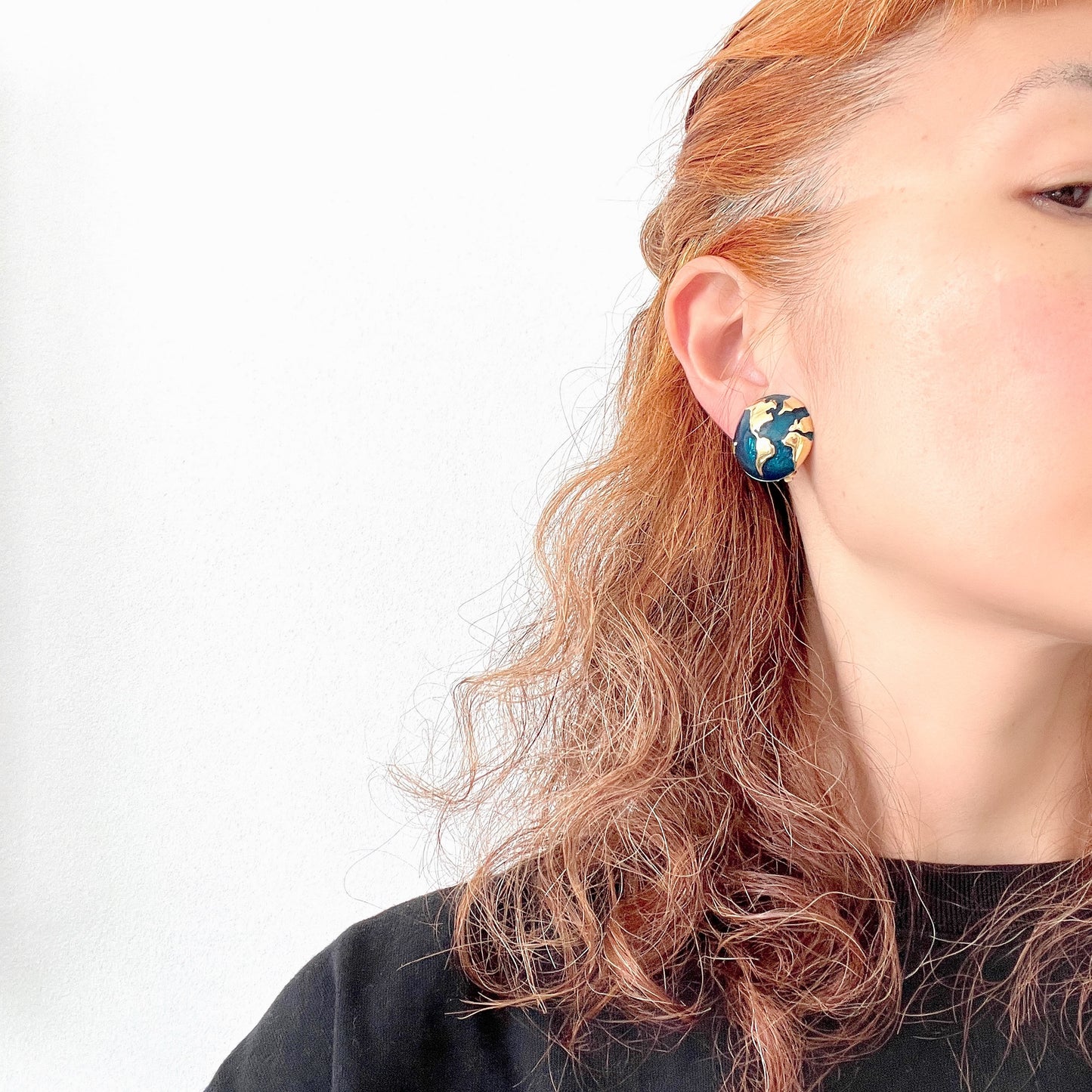 Clip-on earrings featuring a globe design with gold tone continents over a dome of deep ocean blue enamel. 深い海の色のエナメルドームにゴールドトーンで大陸をあしらった地球のクリップイヤリング。