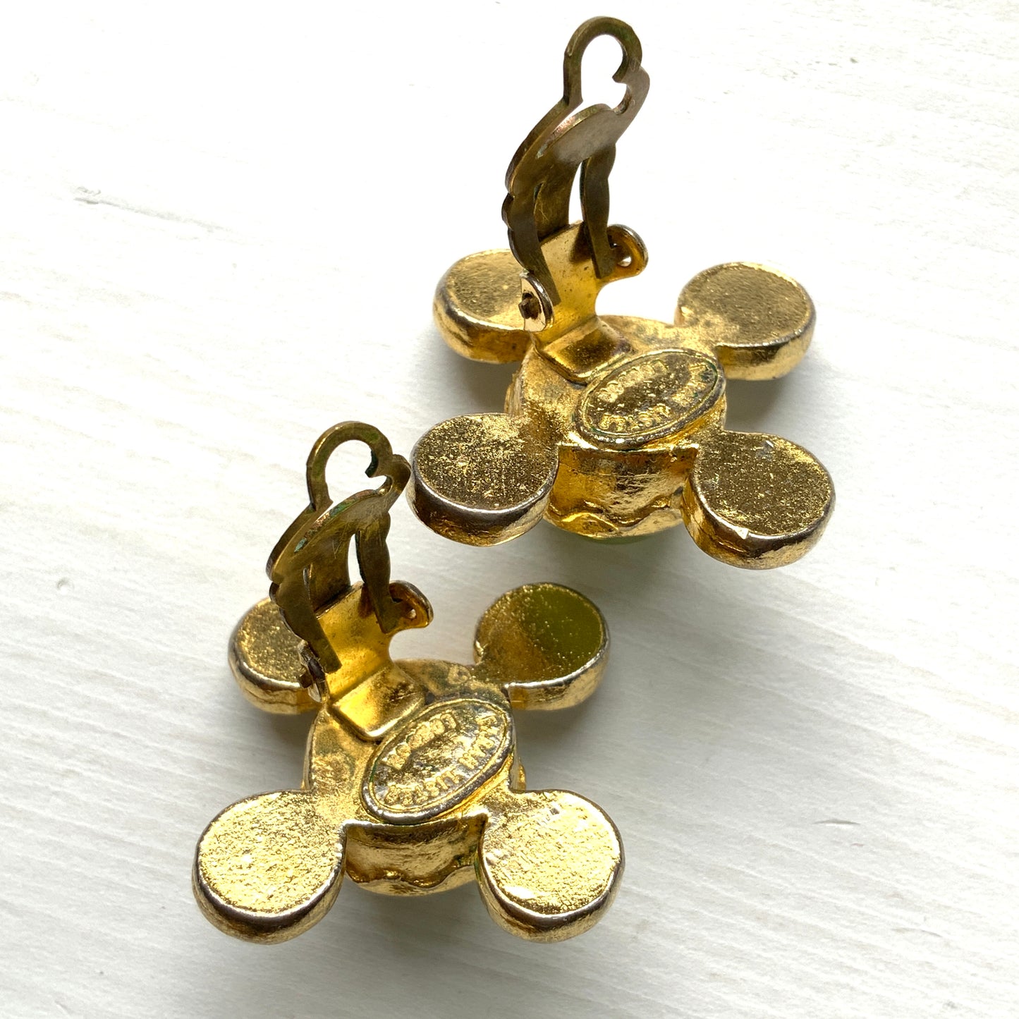 These clip-on earrings by Farah Lister feature a striking cross design with a refreshing apple green satin cabochon glass at the centre, paired with vivid turquoise glass stones. 爽やかなアップルグリーンのサテンカボショングラスとヴィヴィッドなターコイズグラスがクロスになった、ファラー・リスターのクリップイヤリング。
