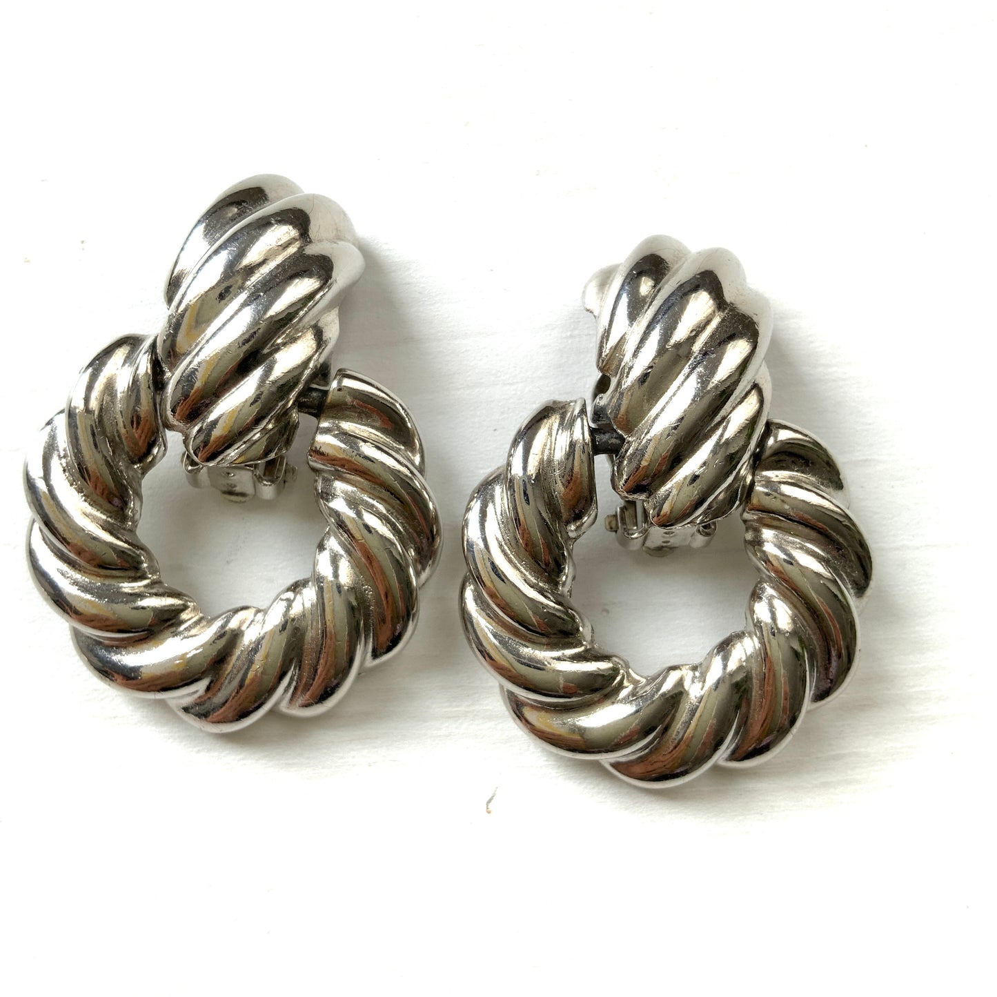 Twisted silver-tone metal door knocker-style clip-on earrings. ツイストされたシルバートーンメタルのドアノッカー型クリップイヤリング。