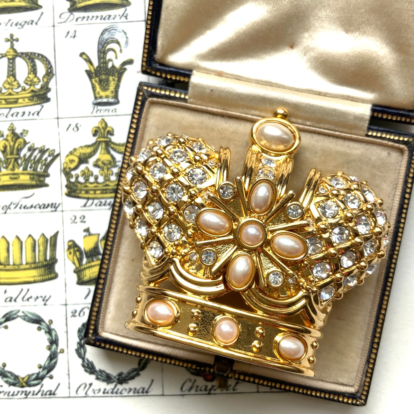 A crown brooch adorned with pearl cabochons and clear rhinestones on gold-tone metal. ゴールドトーンメタルに、パールカボションやクリアラインストーンがふんだんにあしらわれたクラウンブローチ。