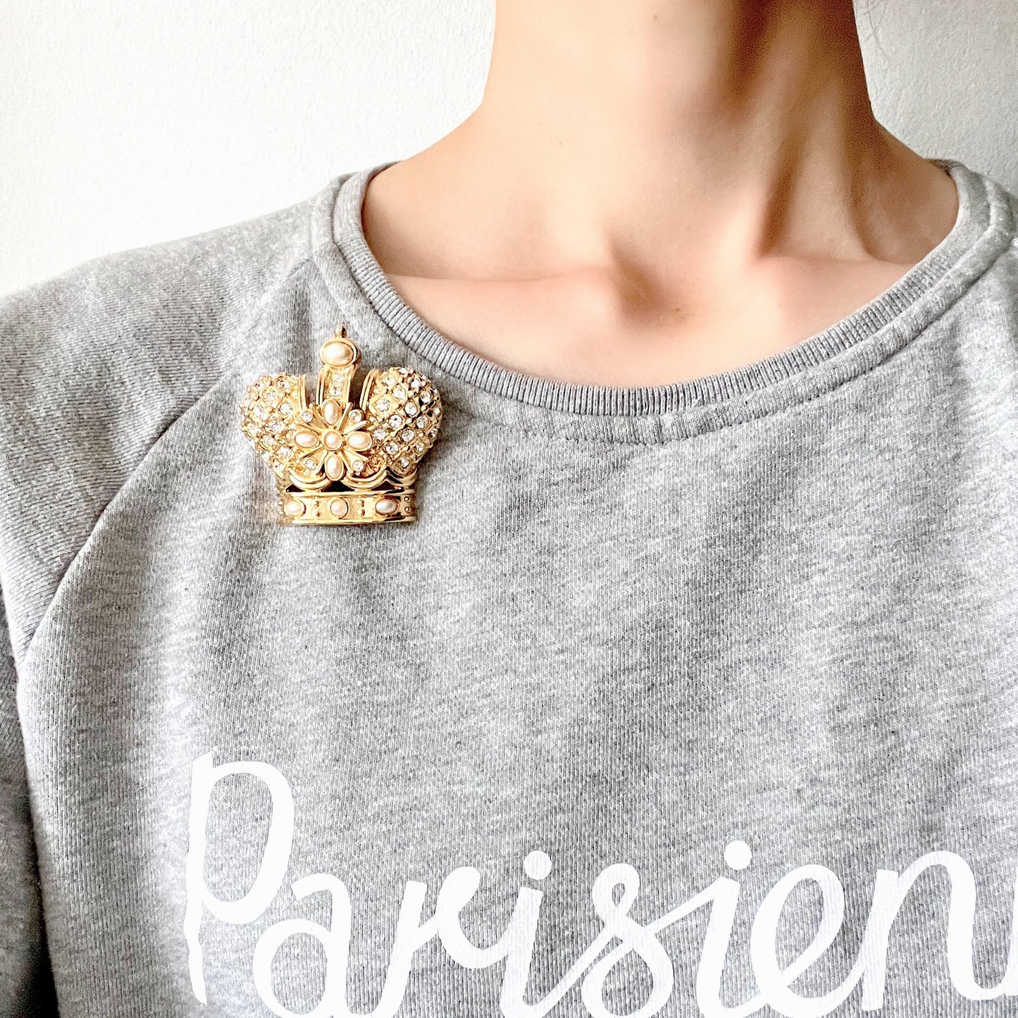 A crown brooch adorned with pearl cabochons and clear rhinestones on gold-tone metal. ゴールドトーンメタルに、パールカボションやクリアラインストーンがふんだんにあしらわれたクラウンブローチ。