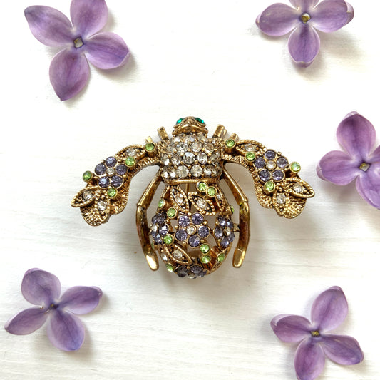 A charming bee brooch adorned with clusters of lilac rhinestone flowers.  ライラックカラーのラインストーンのお花が散りばめられた蜂のブローチ 。
