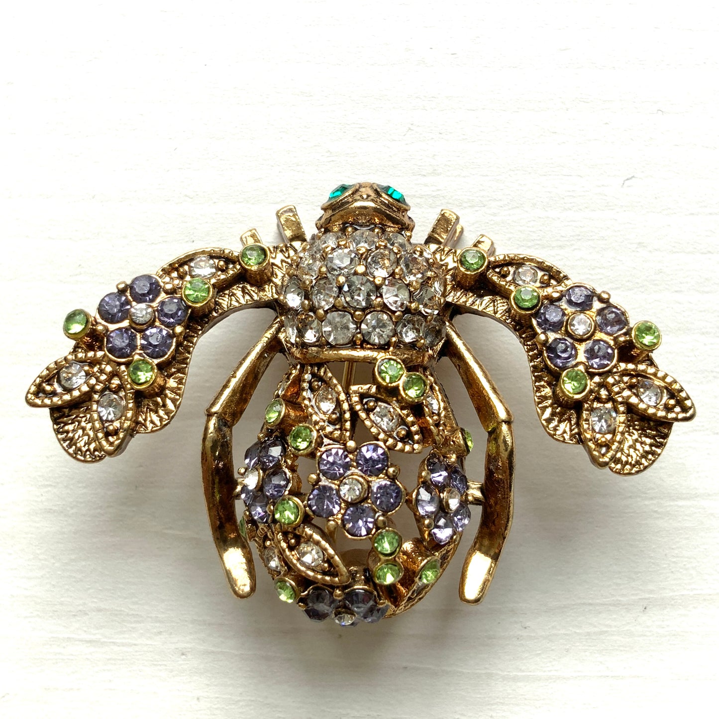 A charming bee brooch adorned with clusters of lilac rhinestone flowers. ライラックカラーのラインストーンのお花が散りばめられた蜂のブローチ 。