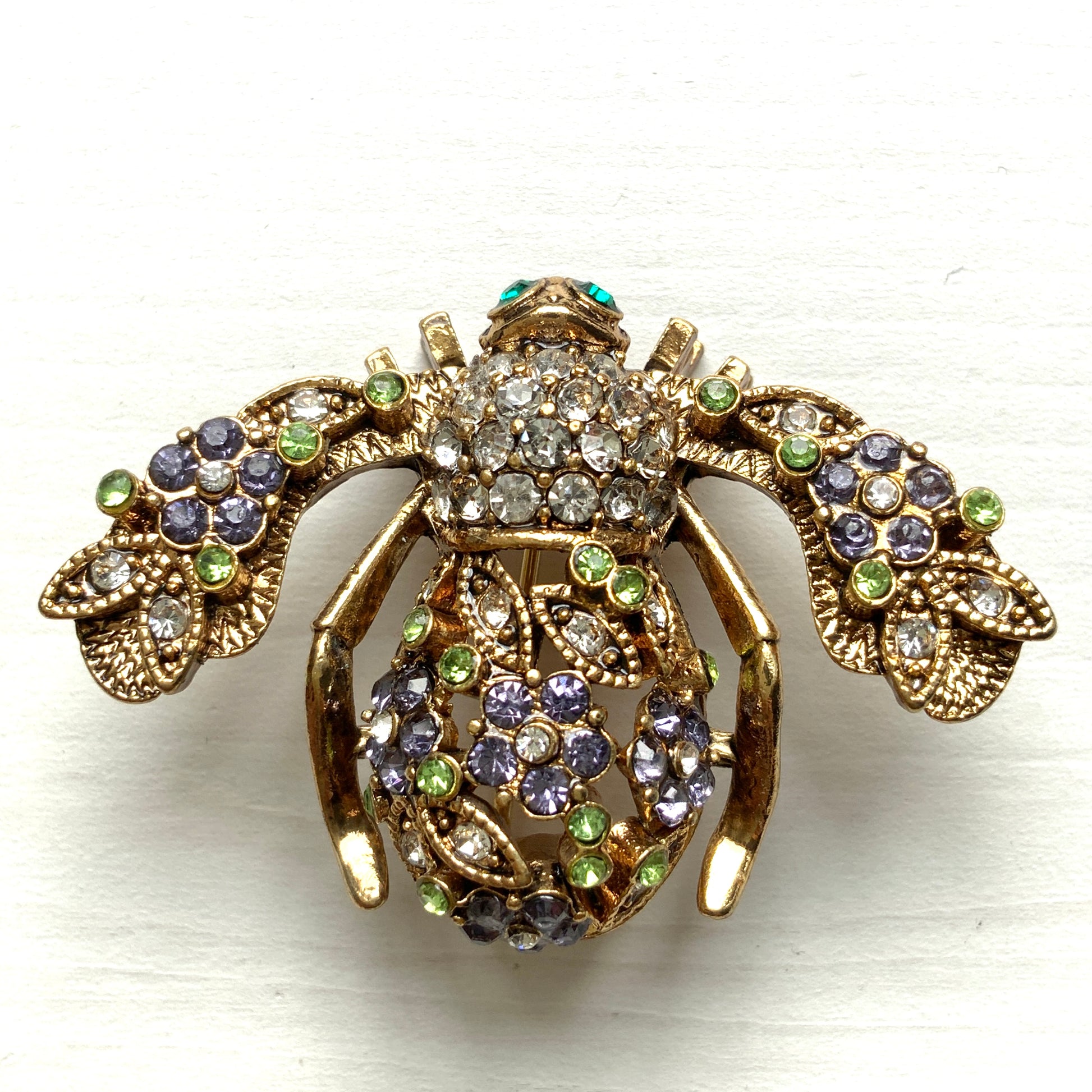 A charming bee brooch adorned with clusters of lilac rhinestone flowers.  ライラックカラーのラインストーンのお花が散りばめられた蜂のブローチ 。