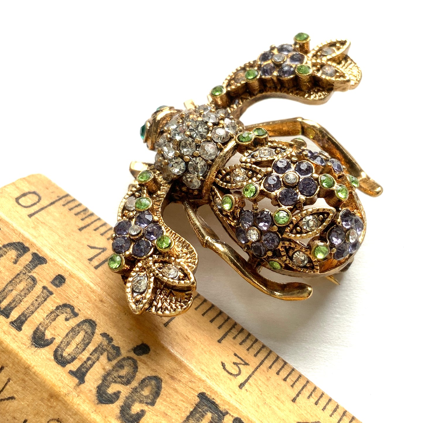 A charming bee brooch adorned with clusters of lilac rhinestone flowers. ライラックカラーのラインストーンのお花が散りばめられた蜂のブローチ 。