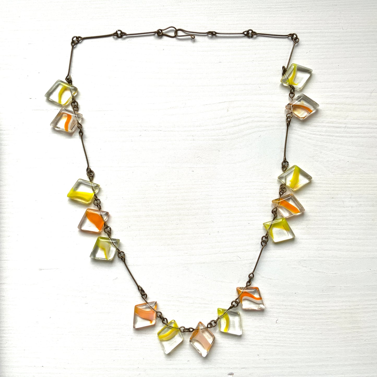 Necklace featuring diamond-shaped clear glass beads infused with shades of yellow, orange, and white. クリアのダイヤ型グラスにイエロー、オレンジ、ホワイトのカラーが入ったビーズを使ったネックレス。