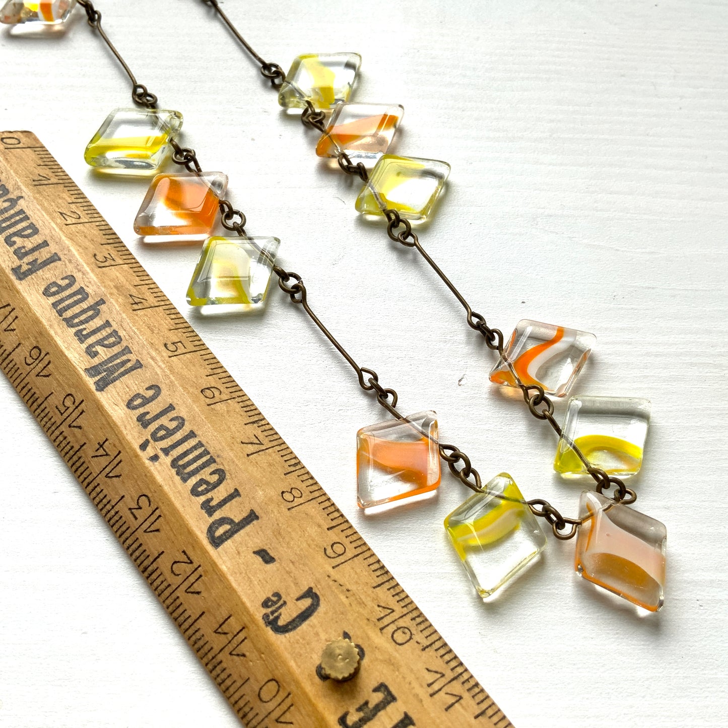 Necklace featuring diamond-shaped clear glass beads infused with shades of yellow, orange, and white. クリアのダイヤ型グラスにイエロー、オレンジ、ホワイトのカラーが入ったビーズを使ったネックレス。