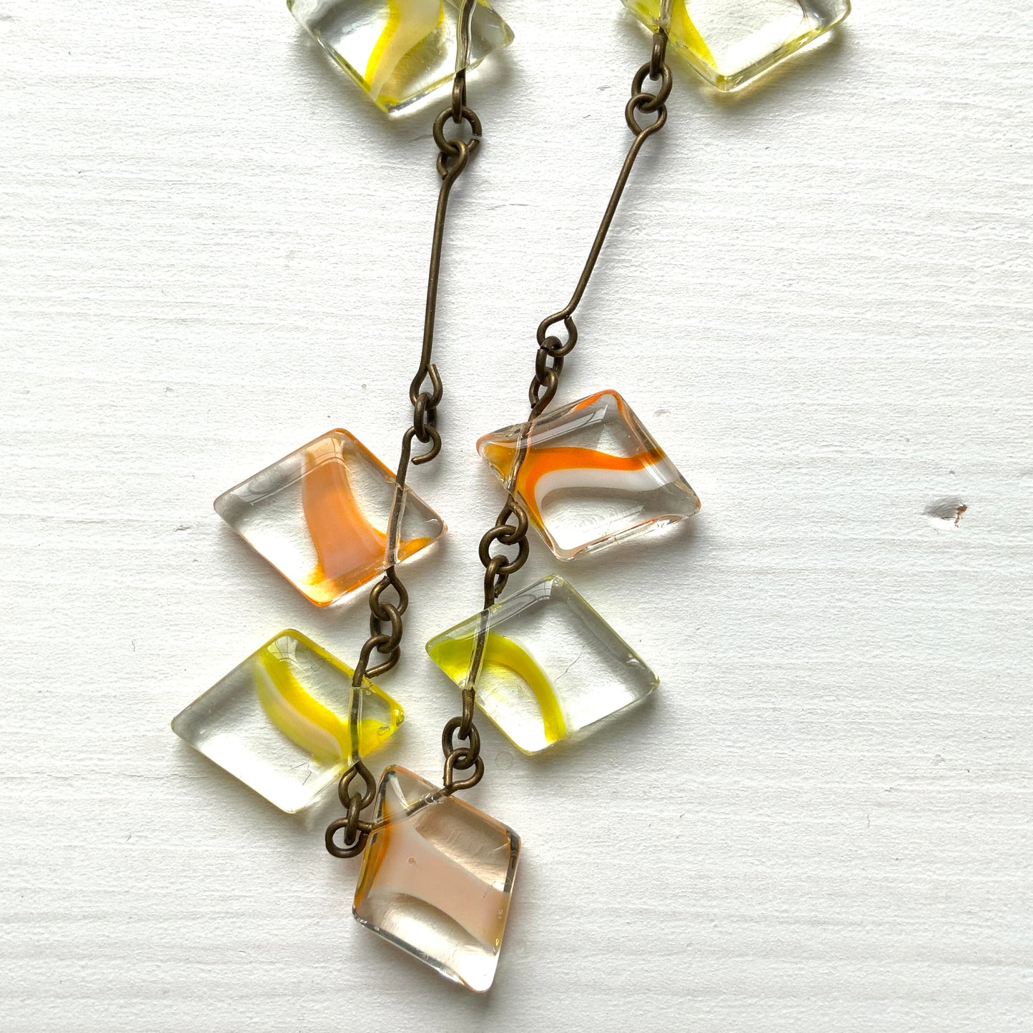 Necklace featuring diamond-shaped clear glass beads infused with shades of yellow, orange, and white. クリアのダイヤ型グラスにイエロー、オレンジ、ホワイトのカラーが入ったビーズを使ったネックレス。