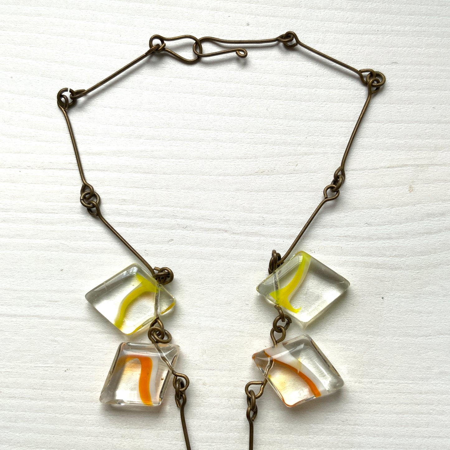 Necklace featuring diamond-shaped clear glass beads infused with shades of yellow, orange, and white. クリアのダイヤ型グラスにイエロー、オレンジ、ホワイトのカラーが入ったビーズを使ったネックレス。