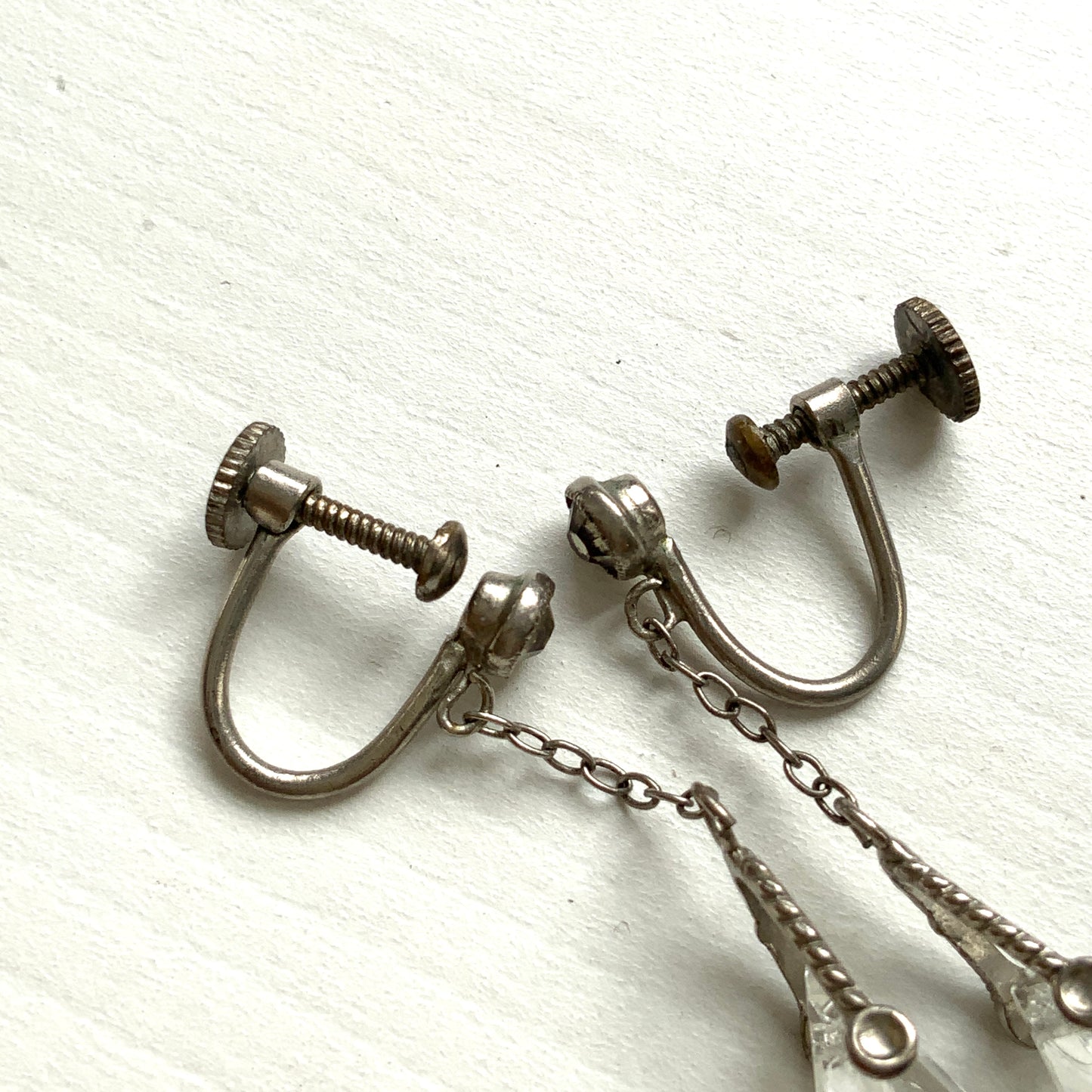 Screw-back earrings featuring clear faceted glass in a unique triangular form. ユニークな三角フォルムのファセットグラスが揺れる、スクリューイヤリング。