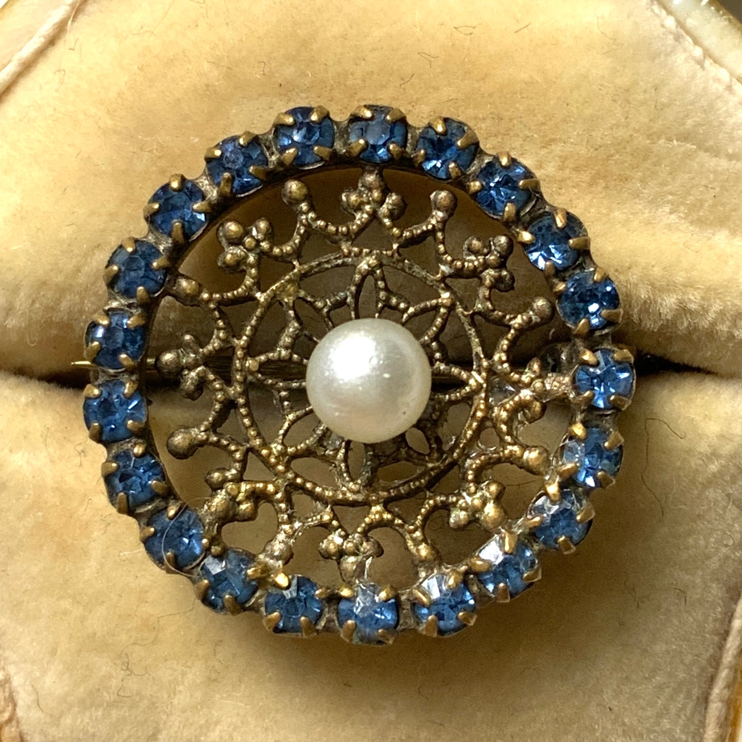 This petite brooch features a delicate round gold-tone filigree, crowned with a small glass pearl. 繊細なラウンドのゴールドトーン フィリグリーに、グラスパールがちょこんと乗ったミニブローチ。