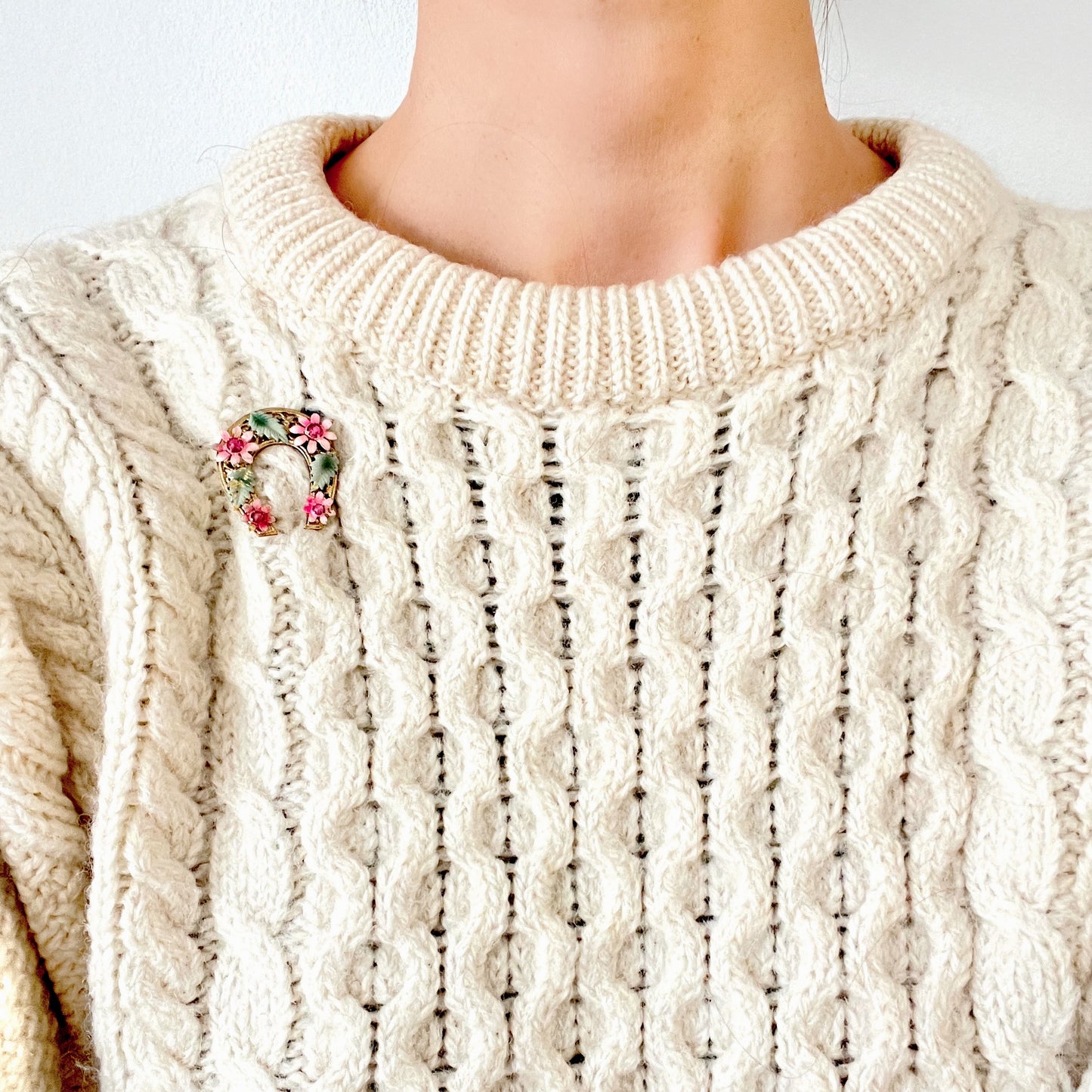 A horseshoe motif brooch adorned with pink enamel flowers. ピンクのエナメルのお花が飾られた、馬蹄モチーフのブローチ。