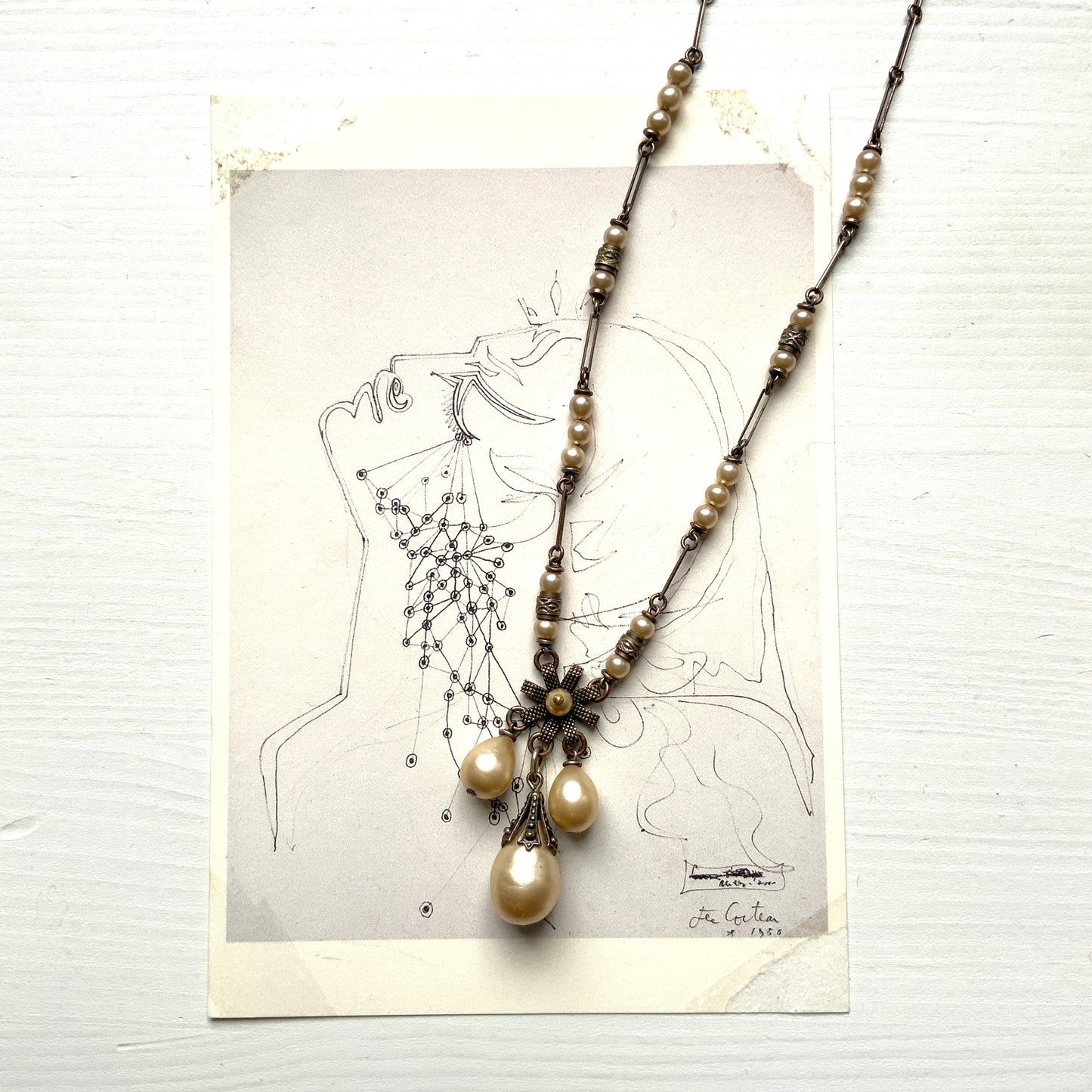 A necklace featuring metal flowers reminiscent of daisies, from which dangle chunky handmade teardrop glass pearls. デイジーのようなメタルのお花に、ゴロンとしたハンドメイドのティアドロップグラスパールがさがったネックレス。