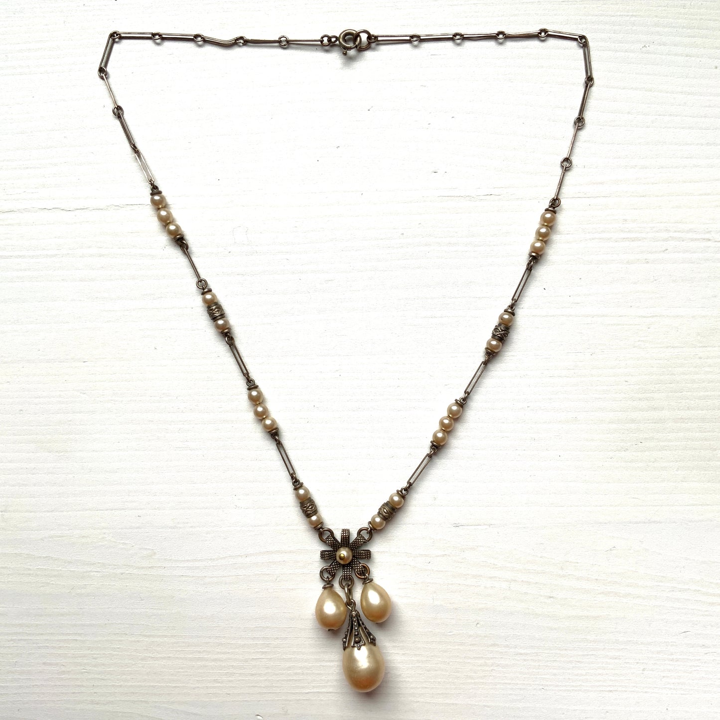 A necklace featuring metal flowers reminiscent of daisies, from which dangle chunky handmade teardrop glass pearls. デイジーのようなメタルのお花に、ゴロンとしたハンドメイドのティアドロップグラスパールがさがったネックレス。