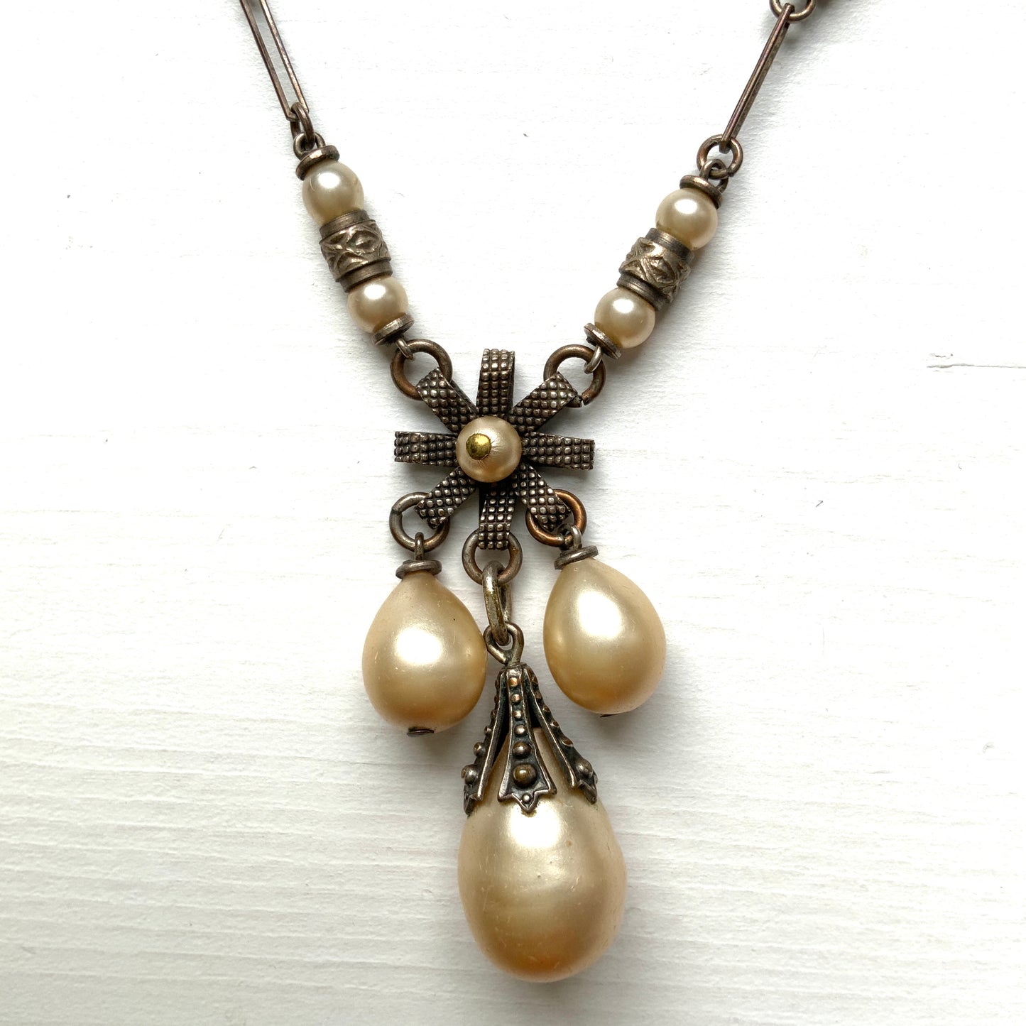 A necklace featuring metal flowers reminiscent of daisies, from which dangle chunky handmade teardrop glass pearls. デイジーのようなメタルのお花に、ゴロンとしたハンドメイドのティアドロップグラスパールがさがったネックレス。