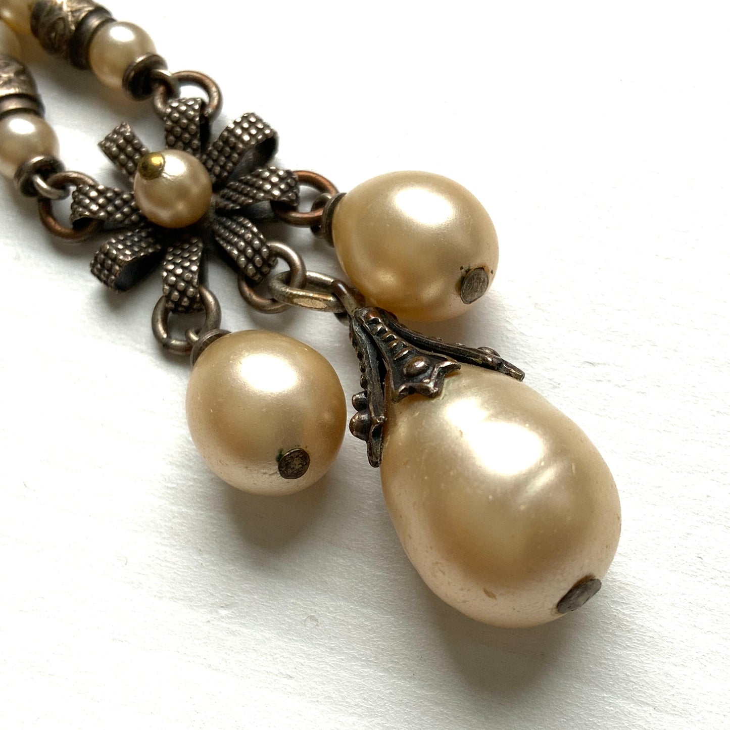 A necklace featuring metal flowers reminiscent of daisies, from which dangle chunky handmade teardrop glass pearls. デイジーのようなメタルのお花に、ゴロンとしたハンドメイドのティアドロップグラスパールがさがったネックレス。