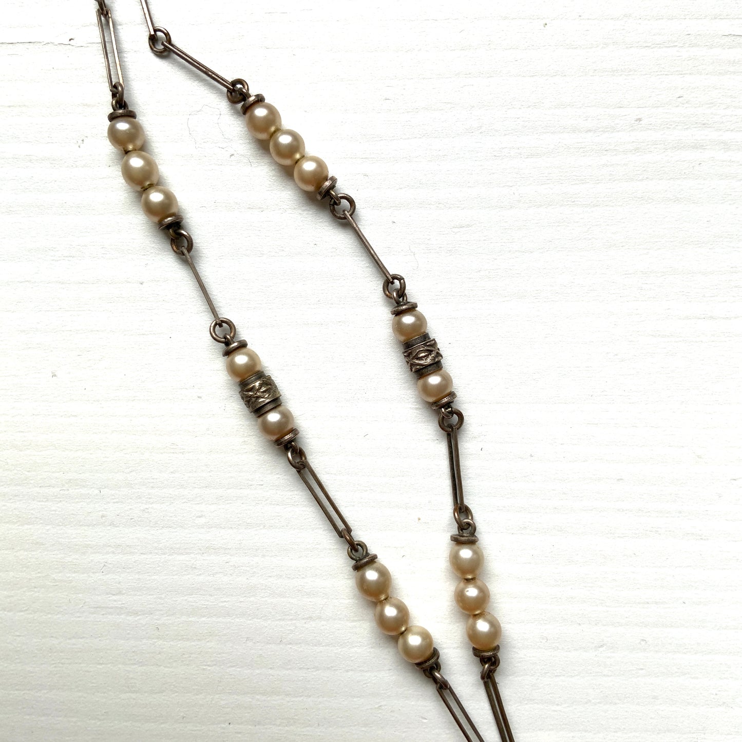 A necklace featuring metal flowers reminiscent of daisies, from which dangle chunky handmade teardrop glass pearls. デイジーのようなメタルのお花に、ゴロンとしたハンドメイドのティアドロップグラスパールがさがったネックレス。
